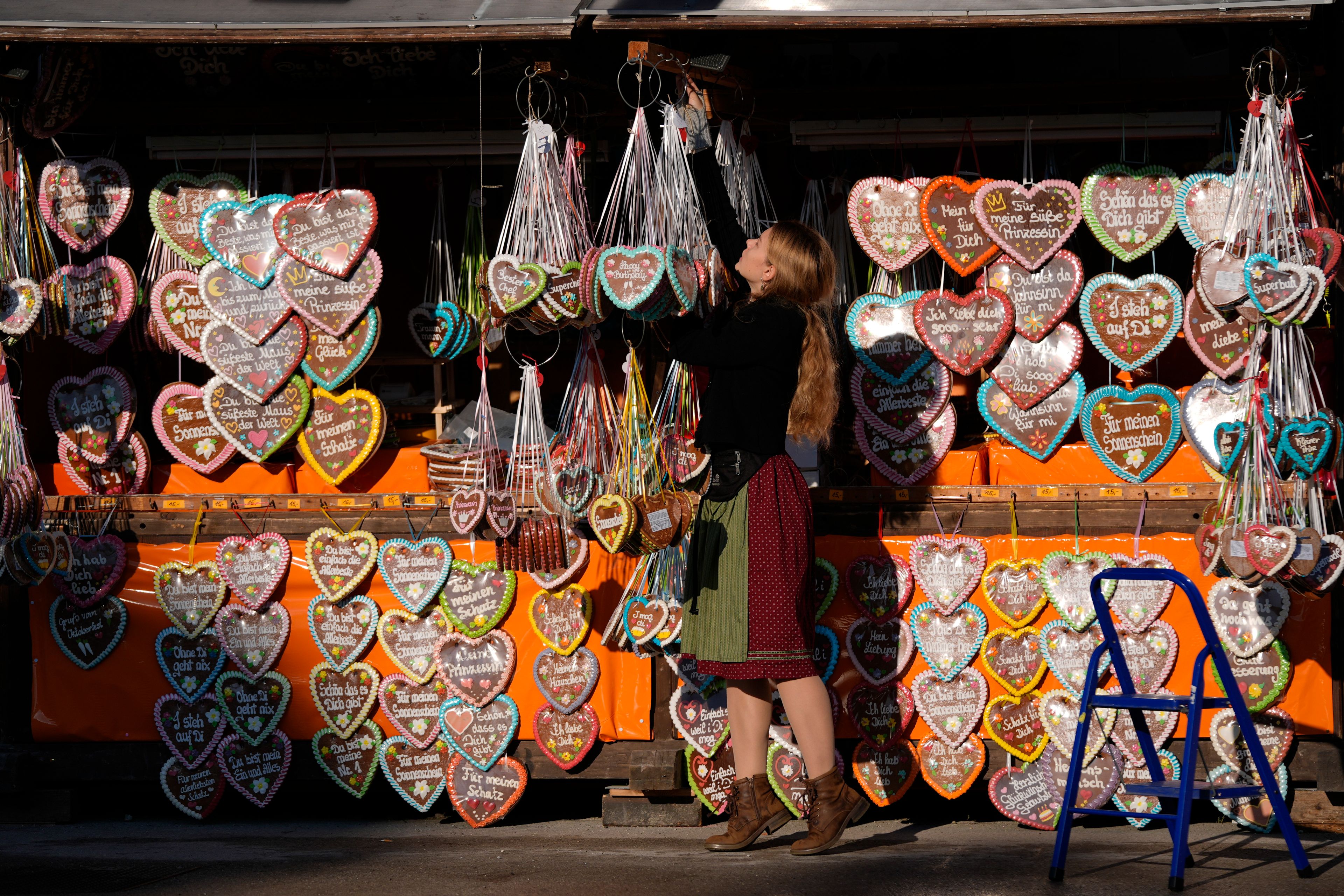 A woman prepares a Gingerbread stand for the start of the 189th 'Oktoberfest' beer festival in Munich, Germany, Saturday, Sept. 21, 2024. (AP Photo/Matthias Schrader)