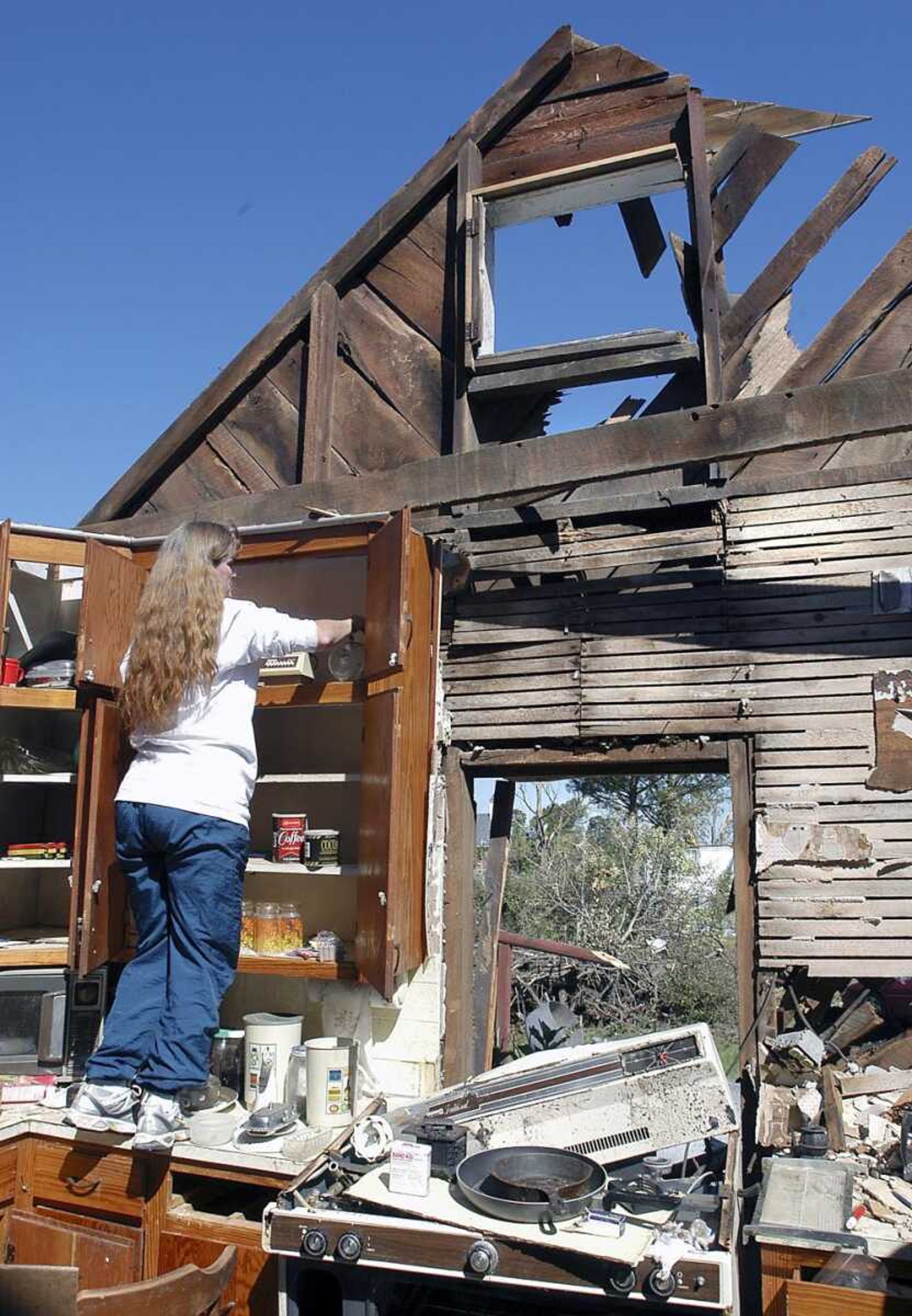 Tammy McCain sorted through the kitchen cabinets of her aunt and uncle's house Sept. 25, 2006, to find items for them to pack up after a tornado destroyed their more than 100-year-old home in Crosstown. Crosstown was hit by a tornado Sept. 22, 2006. (Southeast Missourian, file)