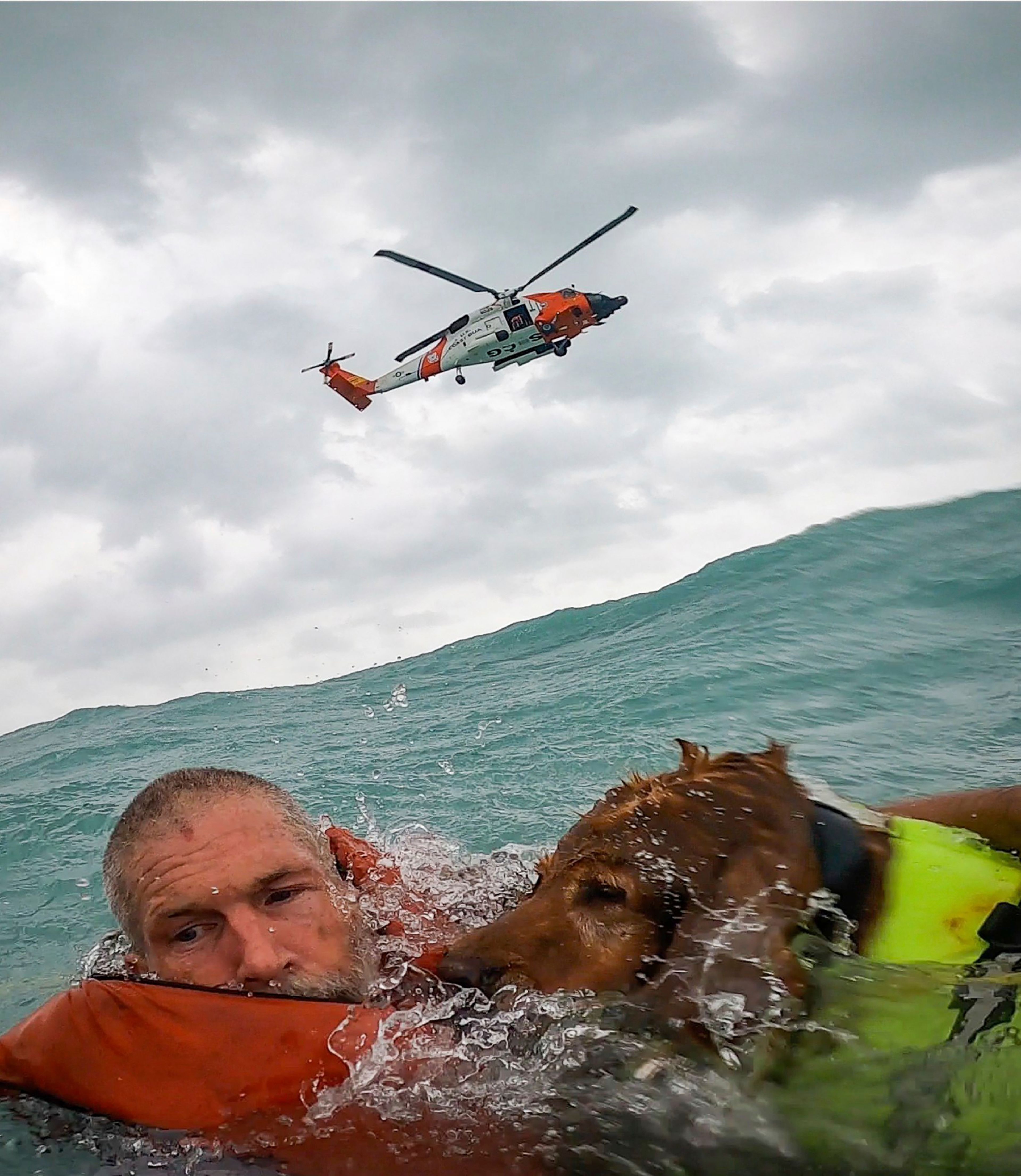 This photo provided by U.S. Coast Guard District Seven (USCGSoutheast) shows a man and his dog being rescued after his sailboat became disabled during Hurricane Helene approximately 25 miles off Sanibel Island, Fla., on Thursday, Sept. 26, 2024. (U.S. Coast Guard District Seven via AP)