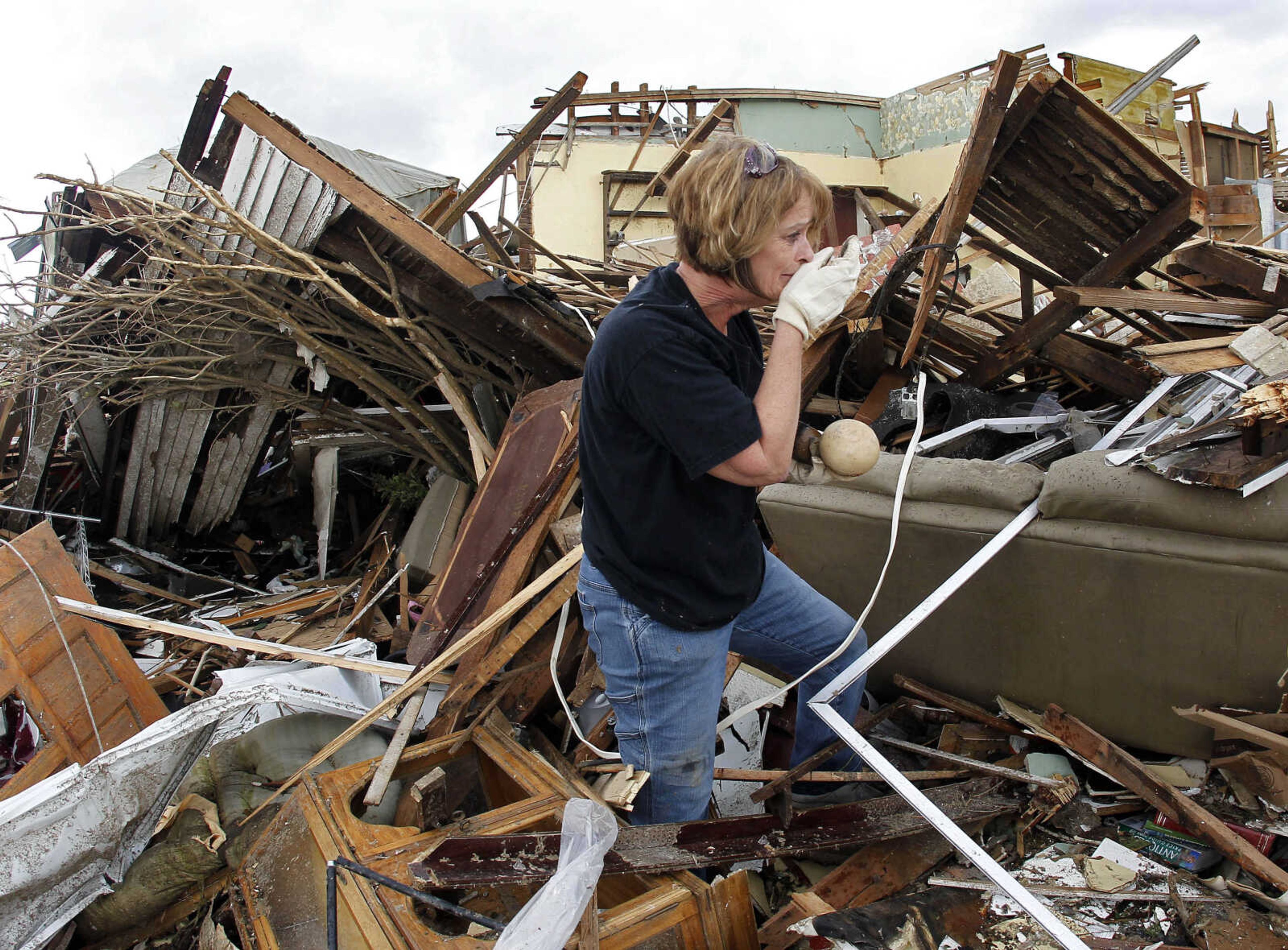 Sandra Pommert reacts to finding a photograph of her parents' farm among the rubble of her sister's tornado-demolished house on Wednesday, May 25, 2011, in Joplin, Mo. Her sister, Judy Flenner, is recovering after having a mild heart attack following Sunday's storm that killed at least 122 people. (AP Photo/Mark Humphrey)