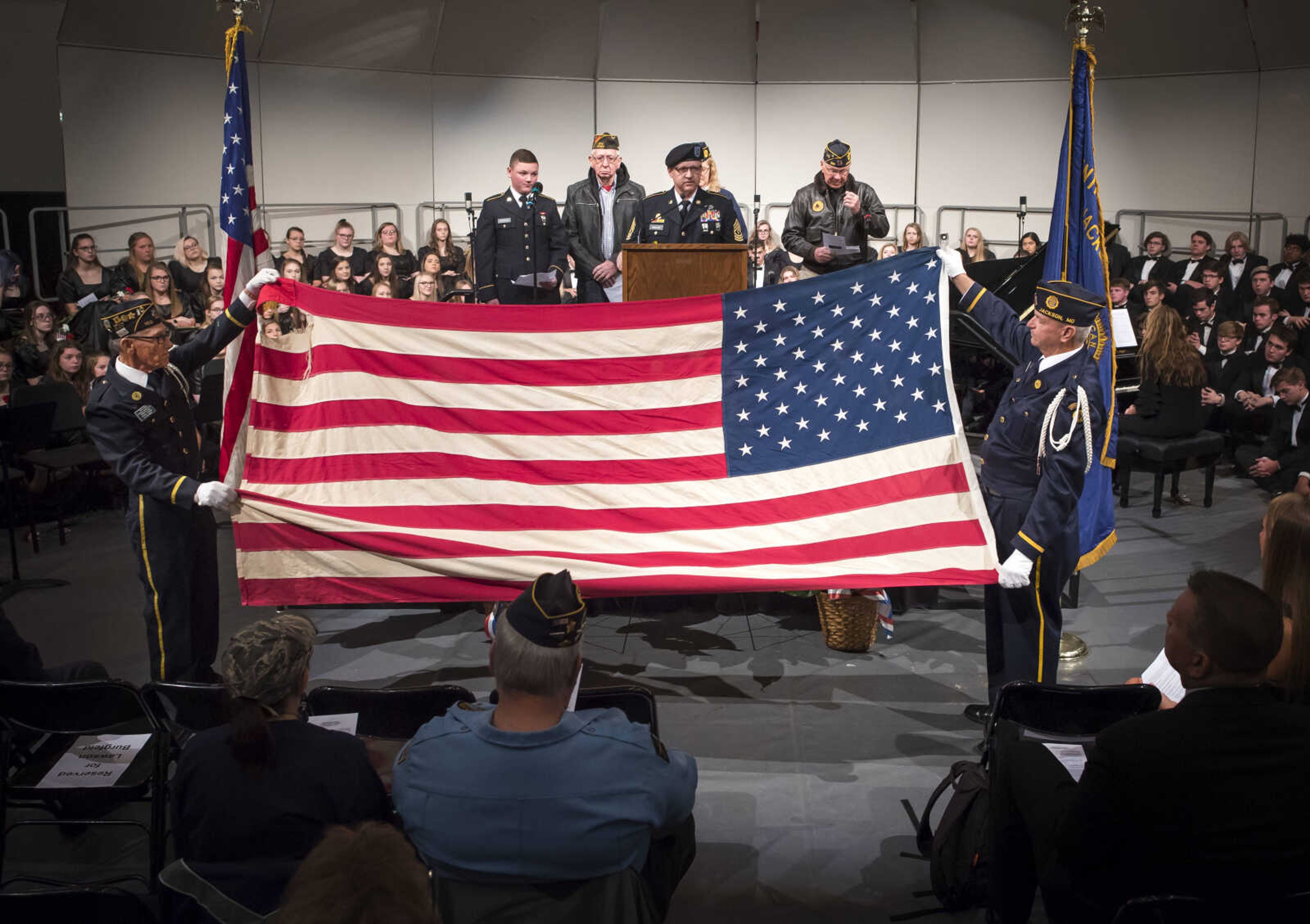 Honor guard members Joe Don Randol, front left, and Dennis Koeberl, far right, hold the American flag as "Ragged Old Flag" is read by, back row from left, Caleb Anderson, Dean Wendel, Wayne Walley, Penny Kurre and Lawson Burgfeld during an assembly to honor veterans Monday, Nov. 11, 2019, at Jackson High School.