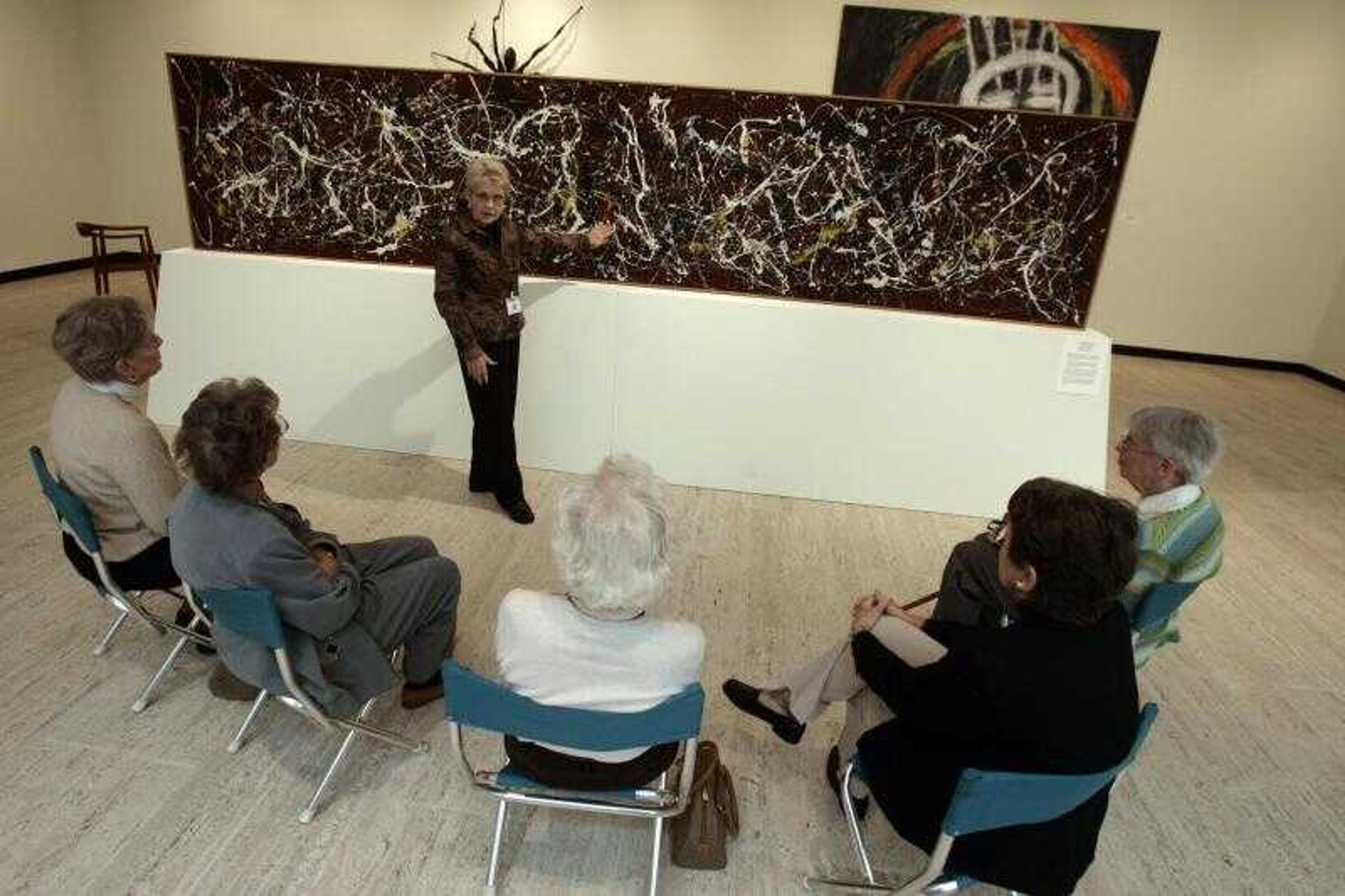 Docent Joan Herrmann talks to a group of women about Jackson Pollock's monumental frieze painting "No. 2, 1949" at the Munson-Williams-Proctor Arts Museum in Utica, N.Y., Oct. 25, 2006.  After undergoing conservation treatment at Williams College in Massachusetts, the museum's flagship masterpiece is back on display.  The museum decided to mount the painting in the middle of a room so that visitors could see the front and back. (AP Photo/  Jim McKnight )