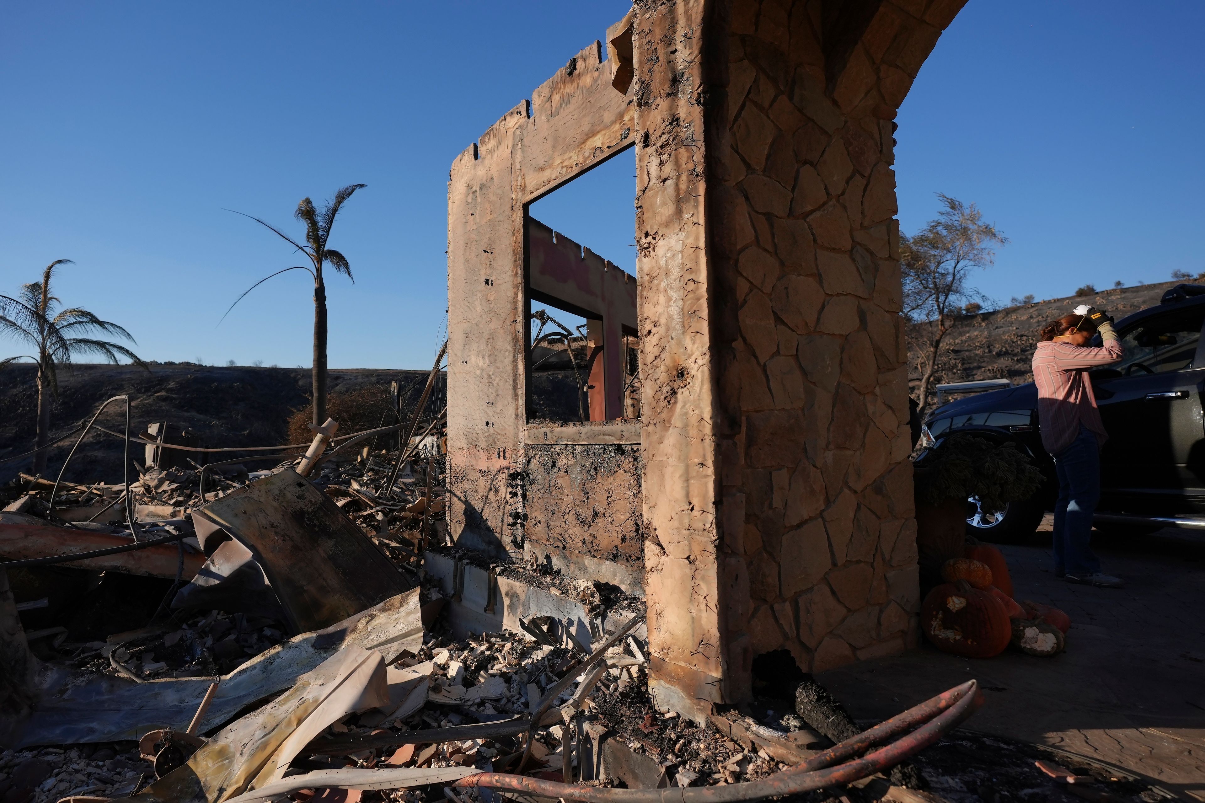 Heidi Nardoni, right, and family friends search her home destroyed by the Mountain Fire in Camarillo, Calif., Nov. 8, 2024. (AP Photo/Jae C. Hong)