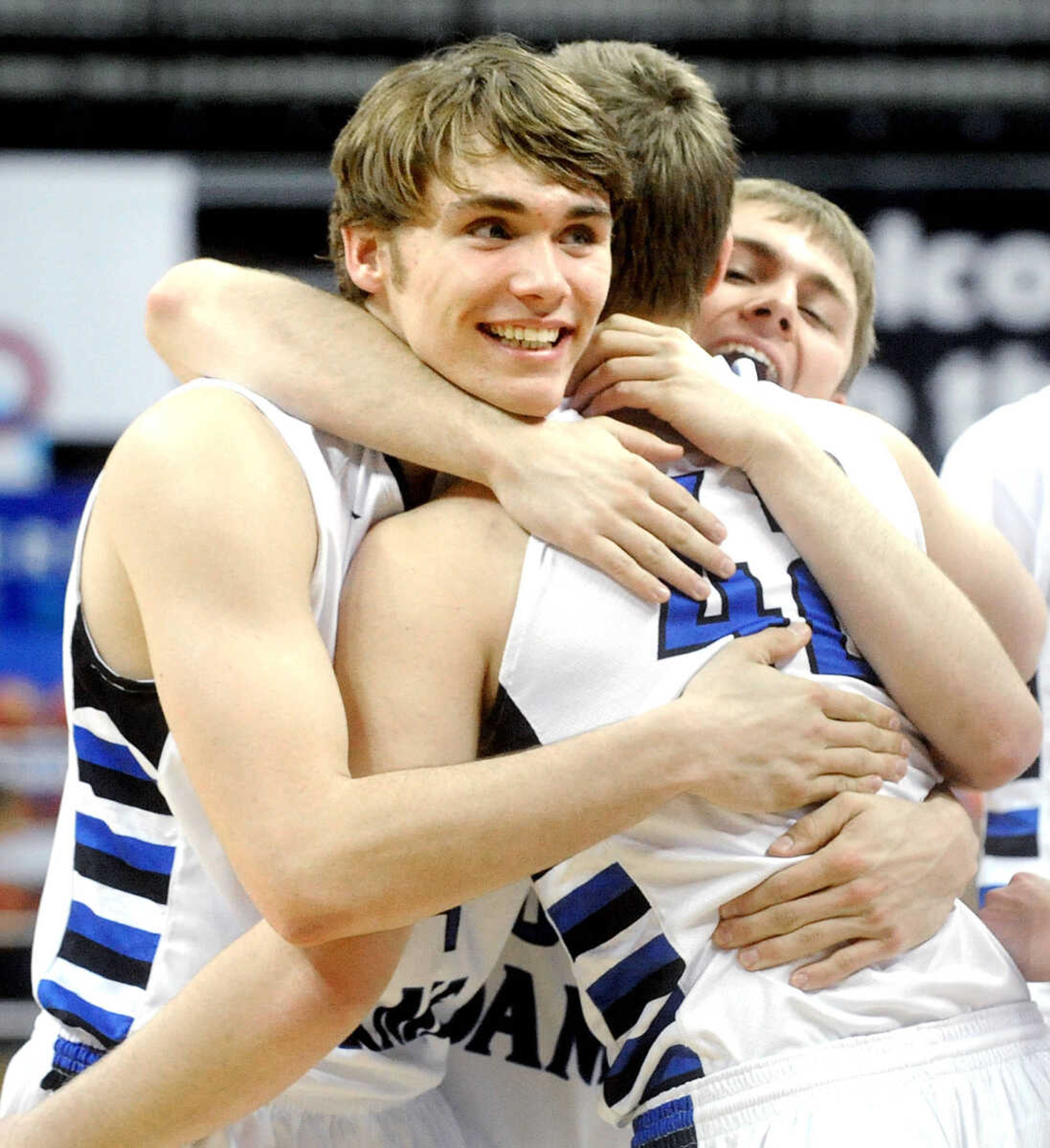 Notre Dame's Dean Crippen, left, and Nick Bradshaw, right, hug Derek Hulshof after the Bulldogs 65-44 Class 4 third place win over Bolivar, Friday, March 20, 2015, in Columbia, Missouri. (Laura Simon)