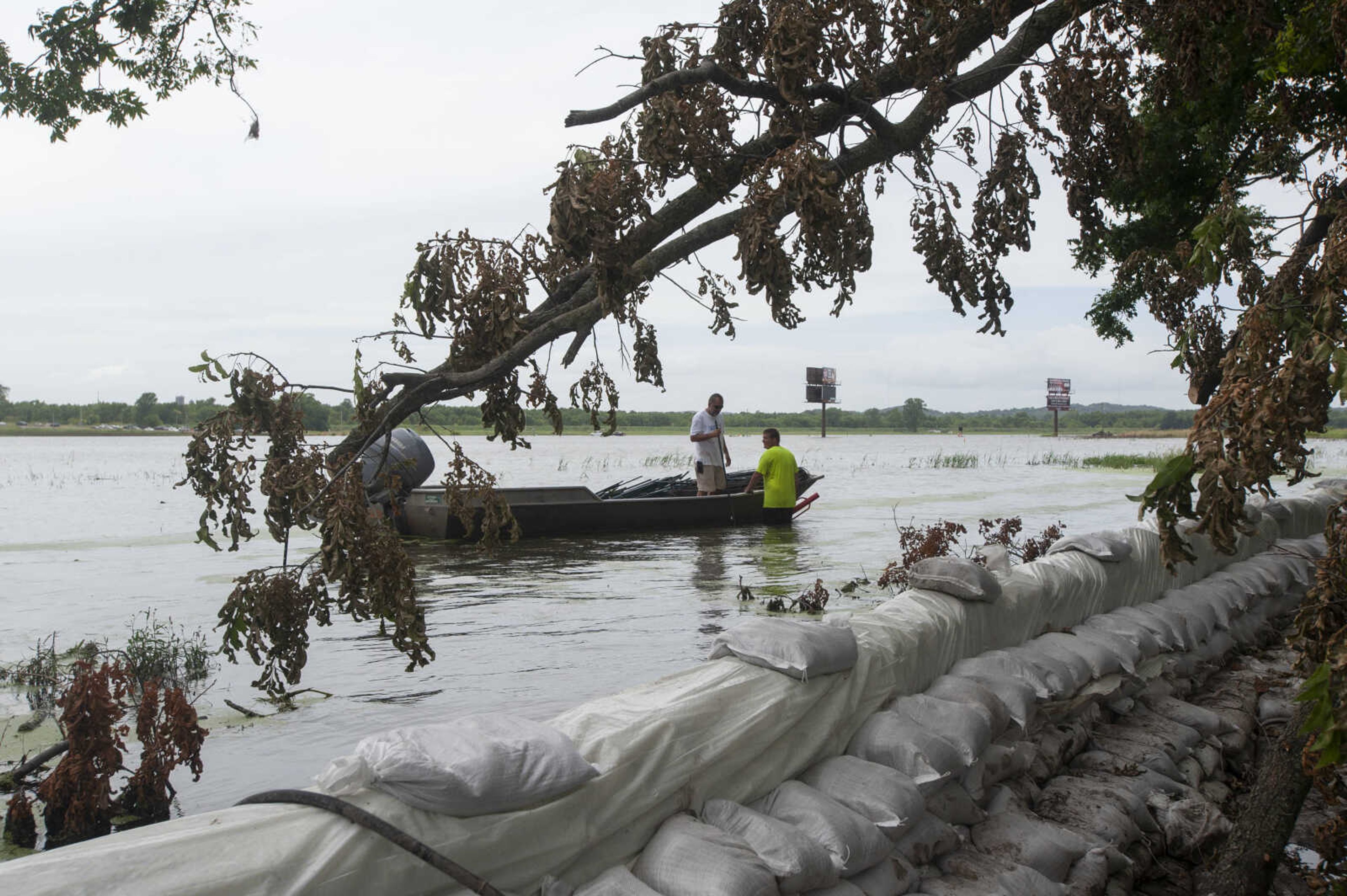 Toby Warner of East Cape Girardeau, Illinois, in water, and Rick Smith of East Cape Girardeau work to install barriers to help slow waves on the floodwaters before the waves hit sandbag walls Sunday, July 14, 2019, in East Cape Girardeau, Illinois.