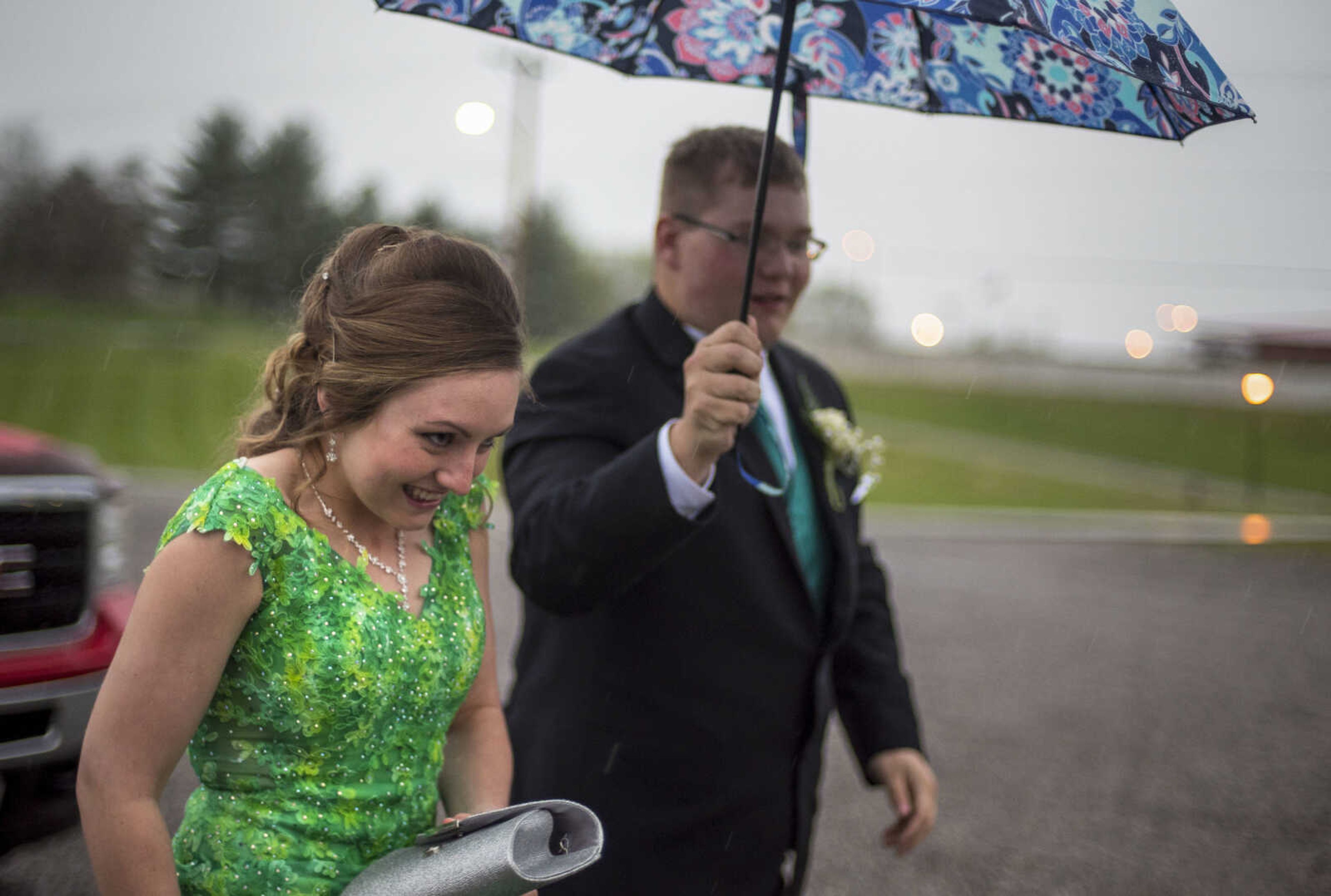 Alexis Lukefahr crosses the parking lot in the rain as her date Hayden Seyer holds an umbrella over her before the Oak Ridge Prom Saturday, April 13, 2019, at the Jackson Elks Lodge in Jackson.