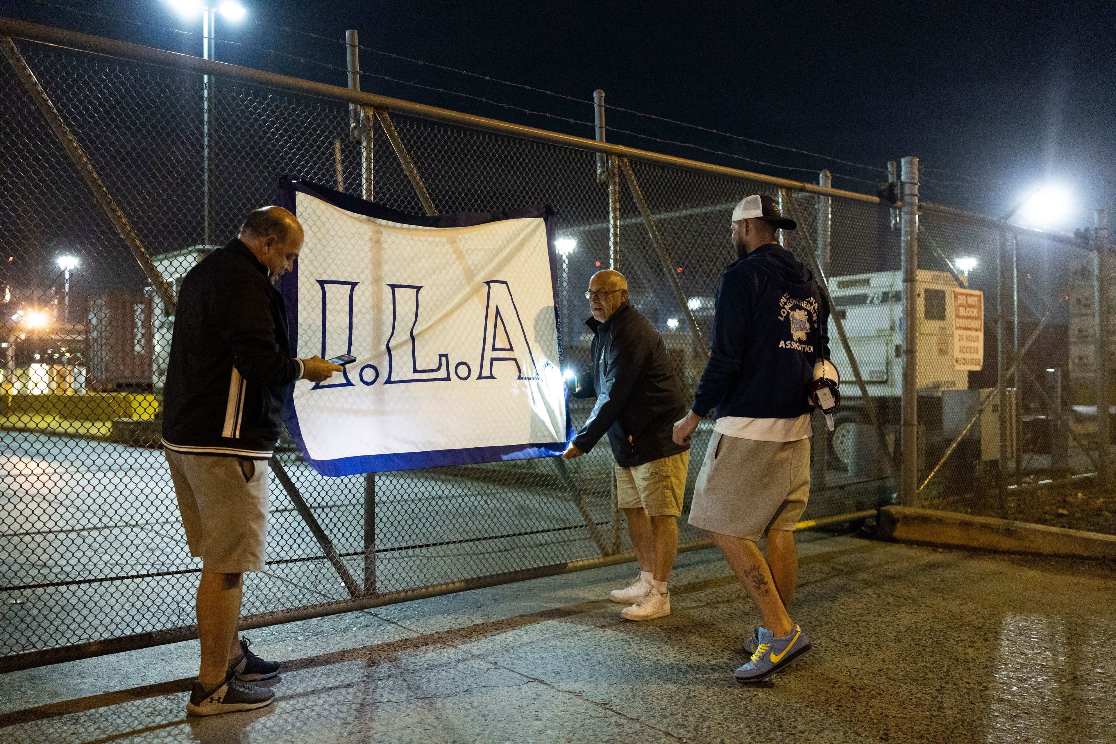 Philadelphia longshoremen hang the flag of the International Longshoremen's Association on a fence outside the Packer Avenue Marine Terminal Port, preparing to strike, as their contract runs out at midnight, Monday, Sept. 30, 2024. (AP Photo/Ryan Collerd)