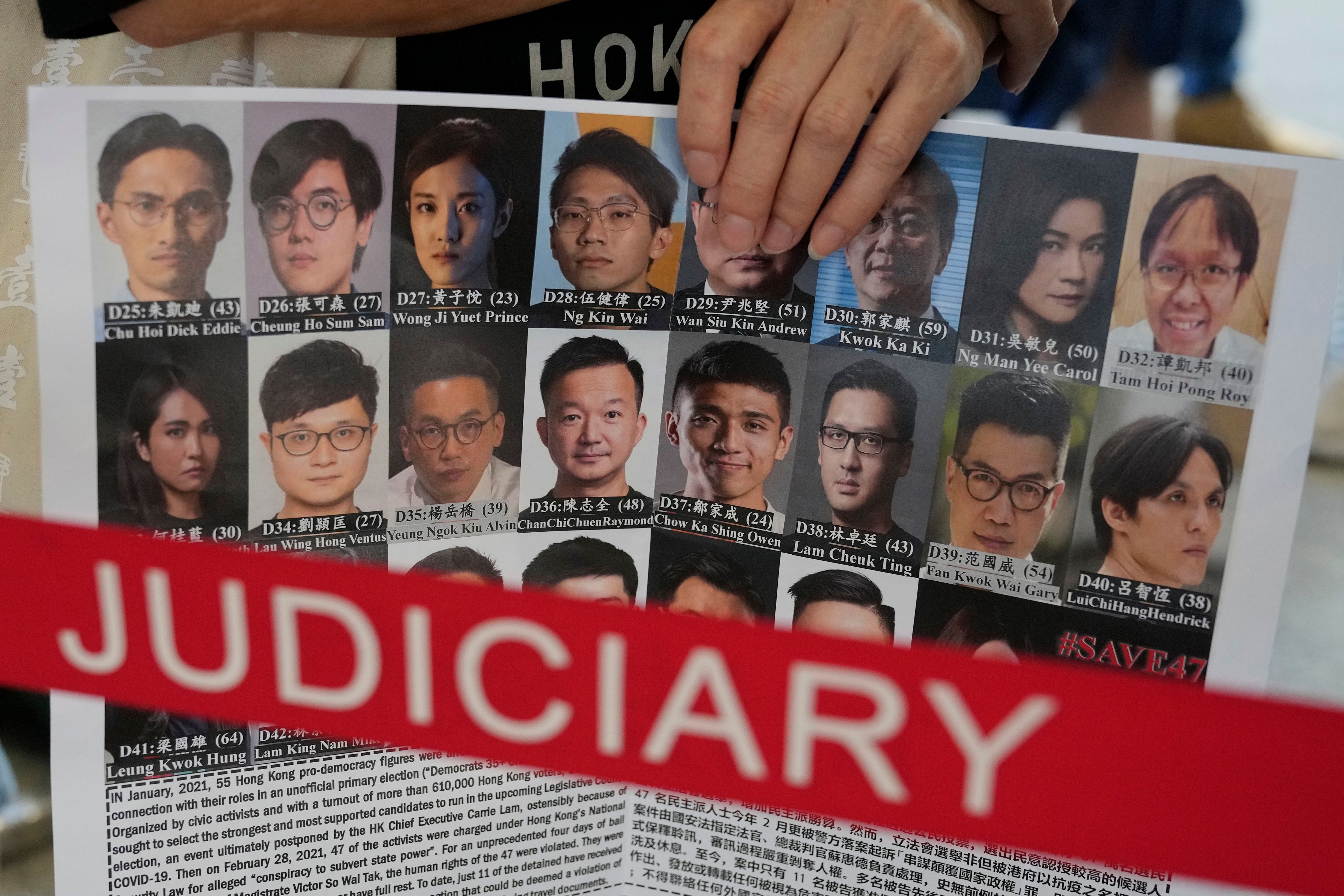 FILE - A supporter holds a placard with the photos of some of the 47 pro-democracy defendants outside a court in Hong Kong, on July 8, 2021. (AP Photo/Kin Cheung, File)