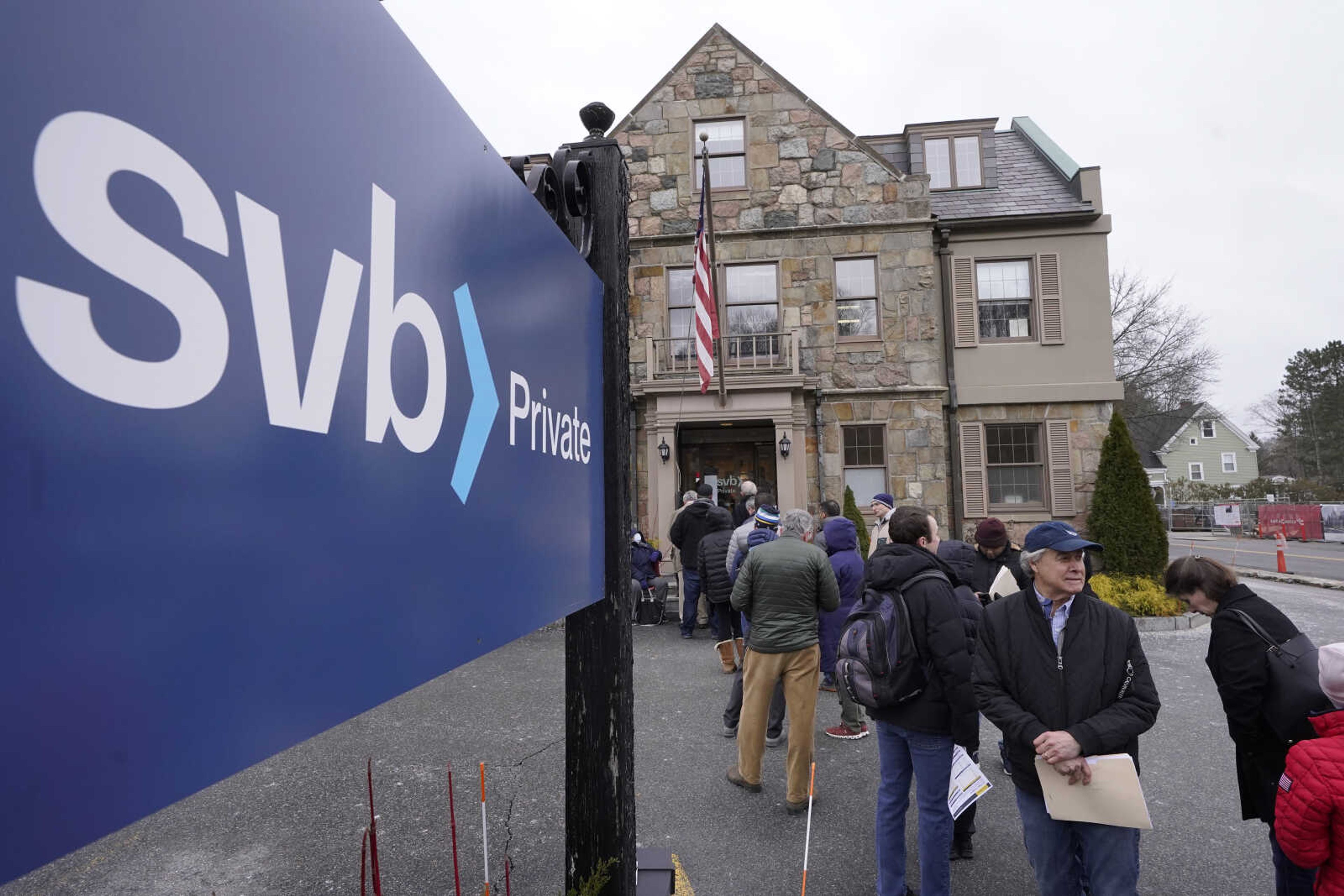 Customers and bystanders form a line outside a Silicon Valley Bank branch location March 13 in Wellesley, Massachusetts. The IMF delivered modest upgrades to the economies of the United States and Europe, which have proven more resilient than expected in the face of higher interest rates and shock of Russia's invasion of Ukraine.