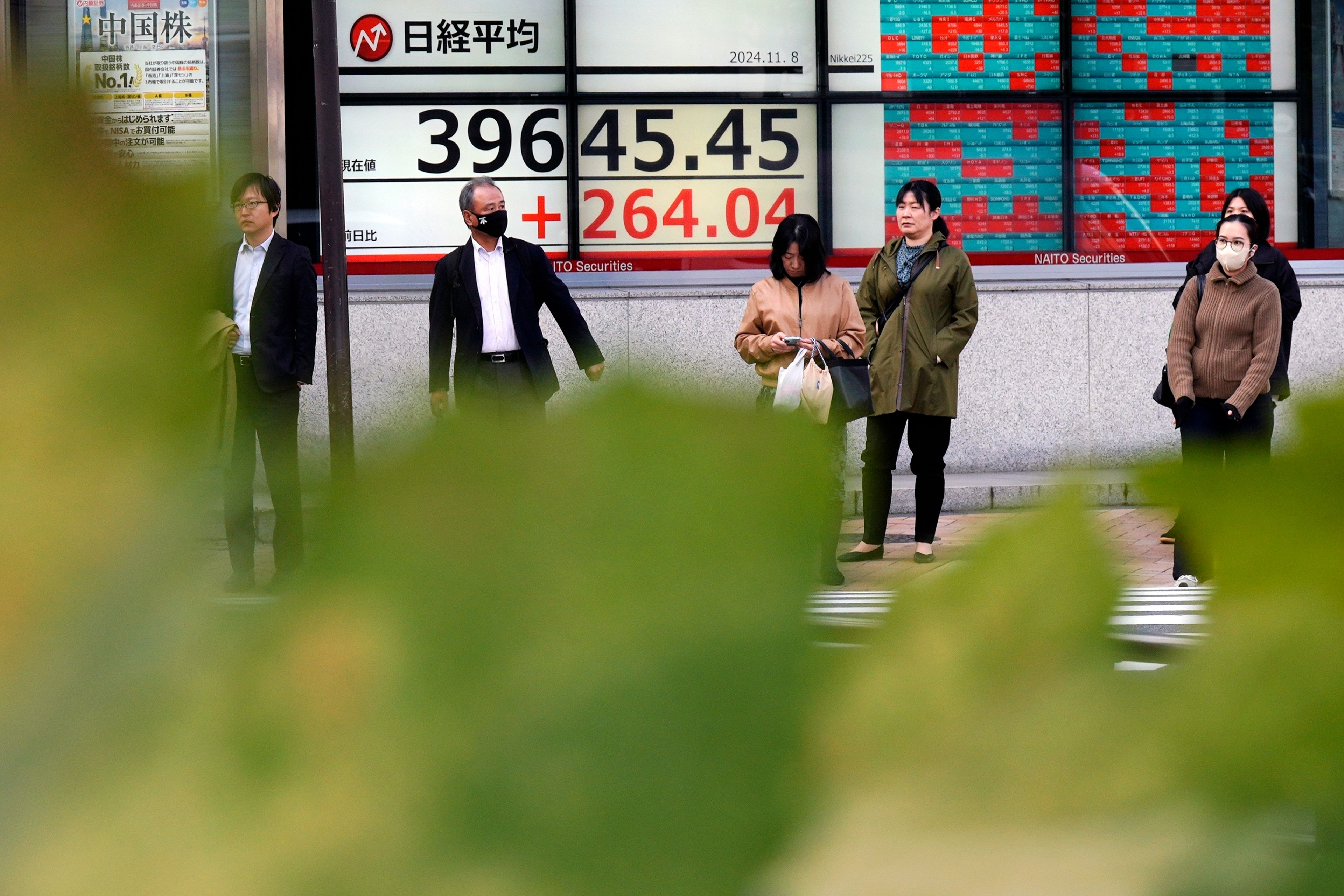 People stand in front of an electronic stock board showing Japan's Nikkei index at a securities firm Friday, Nov. 8, 2024, in Tokyo. (AP Photo/Eugene Hoshiko)