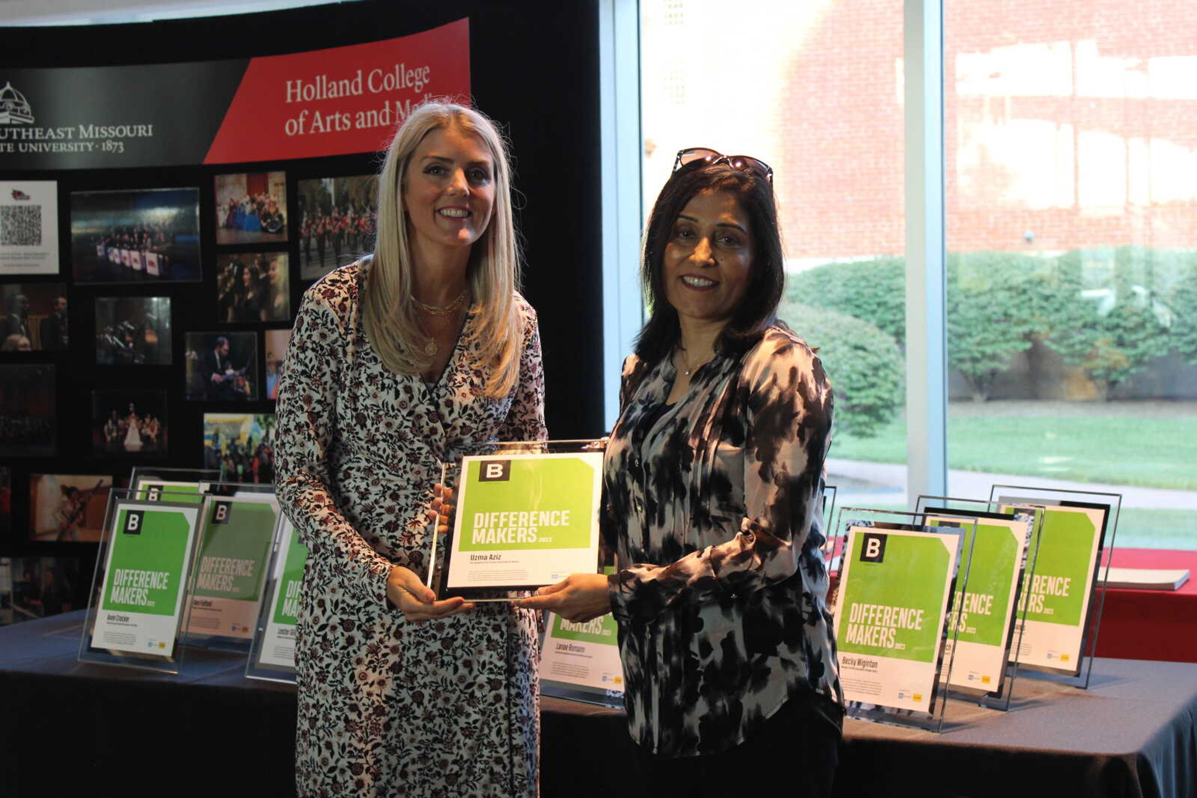 Edward Jones financial advisor Brooke Roth hands Difference Maker Uzma Aziz her award.