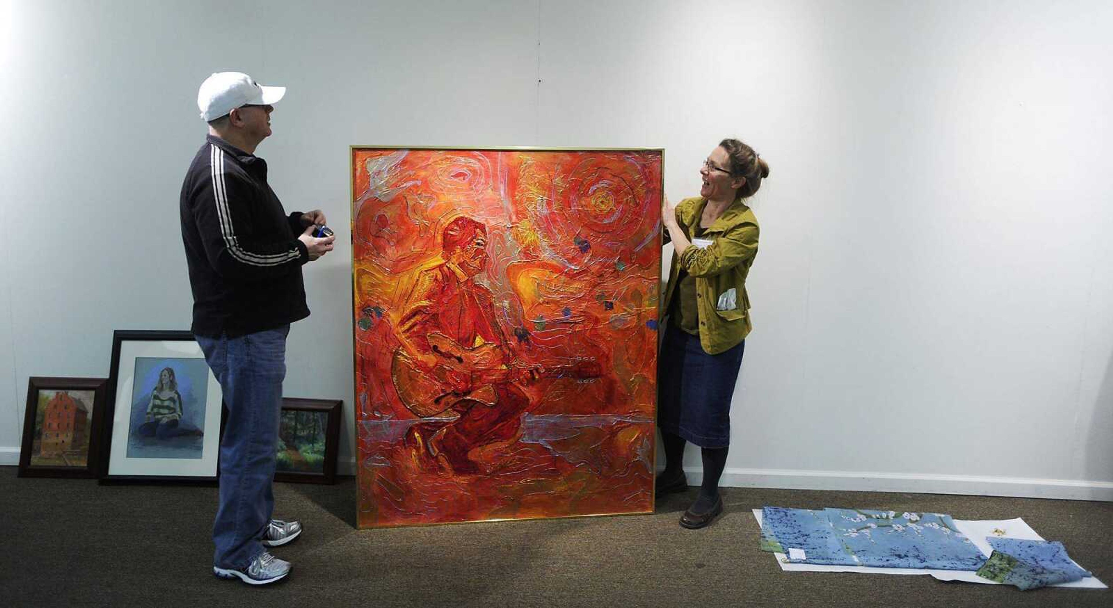 Bob McCool, left, and Mary Ann Hartman prepare to hang Randy Hays' acrylic painting "Chuck Goes to Mardi Gras," March 30 at the Arts Council of Southeast Missouri at 32 North Main St., in Cape Girardeau. Artwork was being dropped off and put on display in preparation for the annual Visual Arts Cooperative show. (ADAM VOGLER)