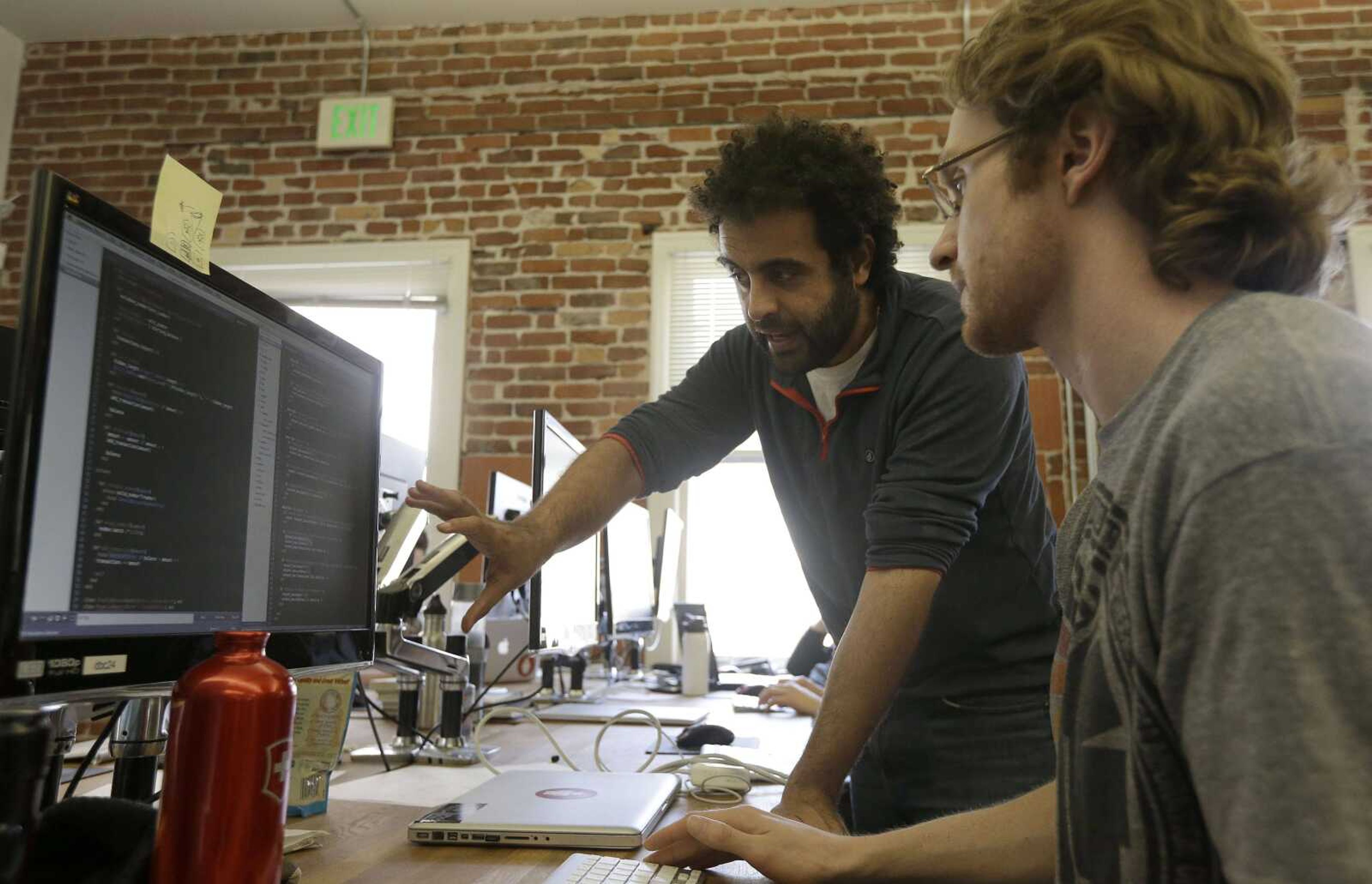 Shereef Bishay, co-founder of Dev Bootcamp, center, talks with student Ryan Guerrettaz during a class at Dev Bootcamp in San Francisco on April 2. Dev Bootcamp is one of a new breed of computer-programming schools that&#8217;s proliferating in U.S. tech hubs. (Jeff Chiu ~ Associated Press)