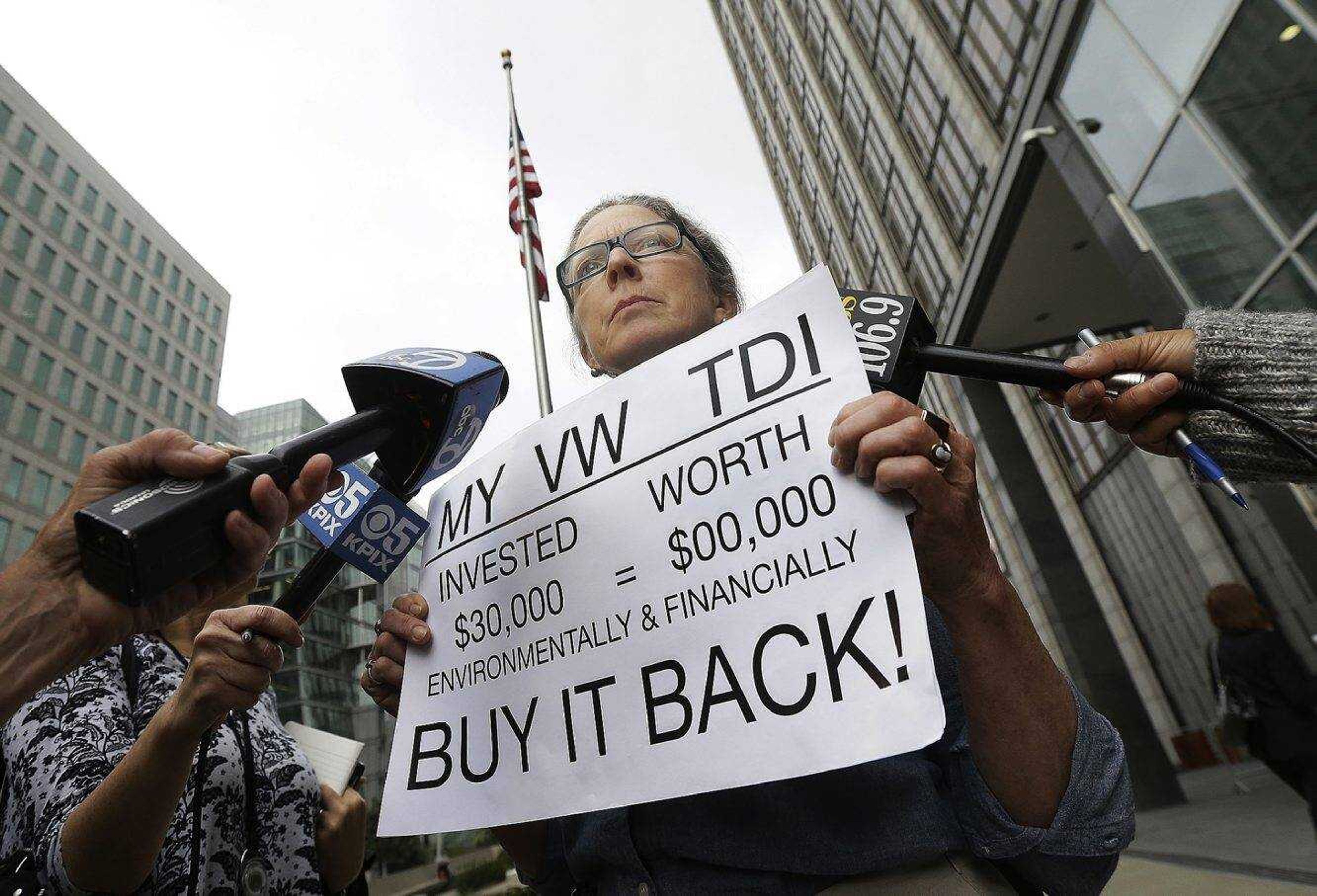 FILE - In this April 21, 2016, file photo, Joyce Ertel Hulbert, owner of a 2015 Volkswagen Golf TDI, holds a sign while interviewed outside of the Phillip Burton Federal Building in San Francisco. A federal judge on Friday, Dec. 16, 2016, planned to hear whether Volkswagen, U.S. regulators and attorneys for vehicle owners had reached a deal for the remaining 80,000 cars caught up in the company'Ã„Ã´s emissions cheating scandal. U.S. District Judge Charles Breyer in San Francisco was set to get an update about the settlement talks.  (AP Photo/Jeff Chiu, File)