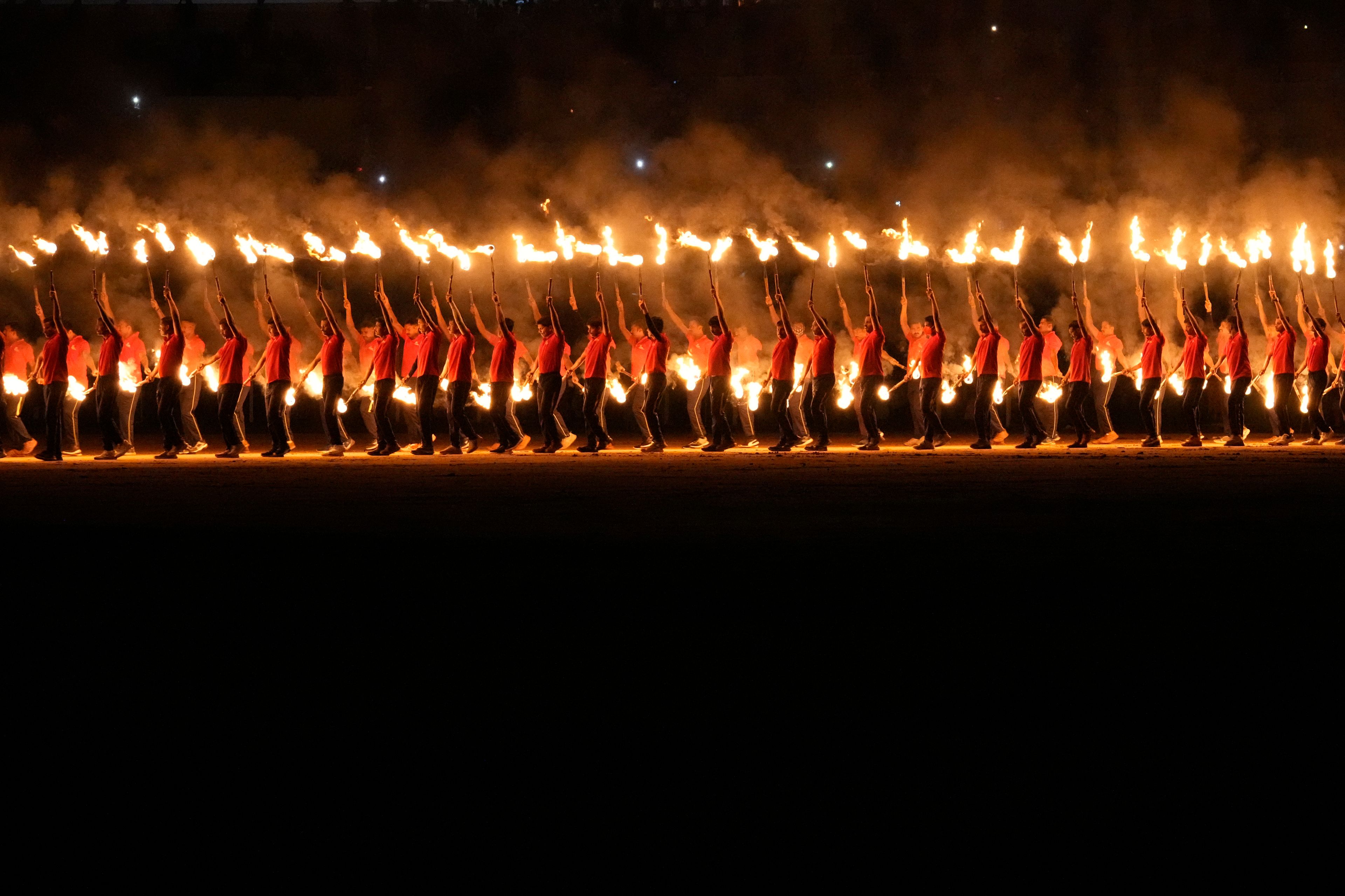 Artists carry burning torches as they perform during a cultural show as part of the Dussehra festivities in Mysuru, India, Friday, Oct. 11, 2024. (AP Photo/Aijaz Rahi)