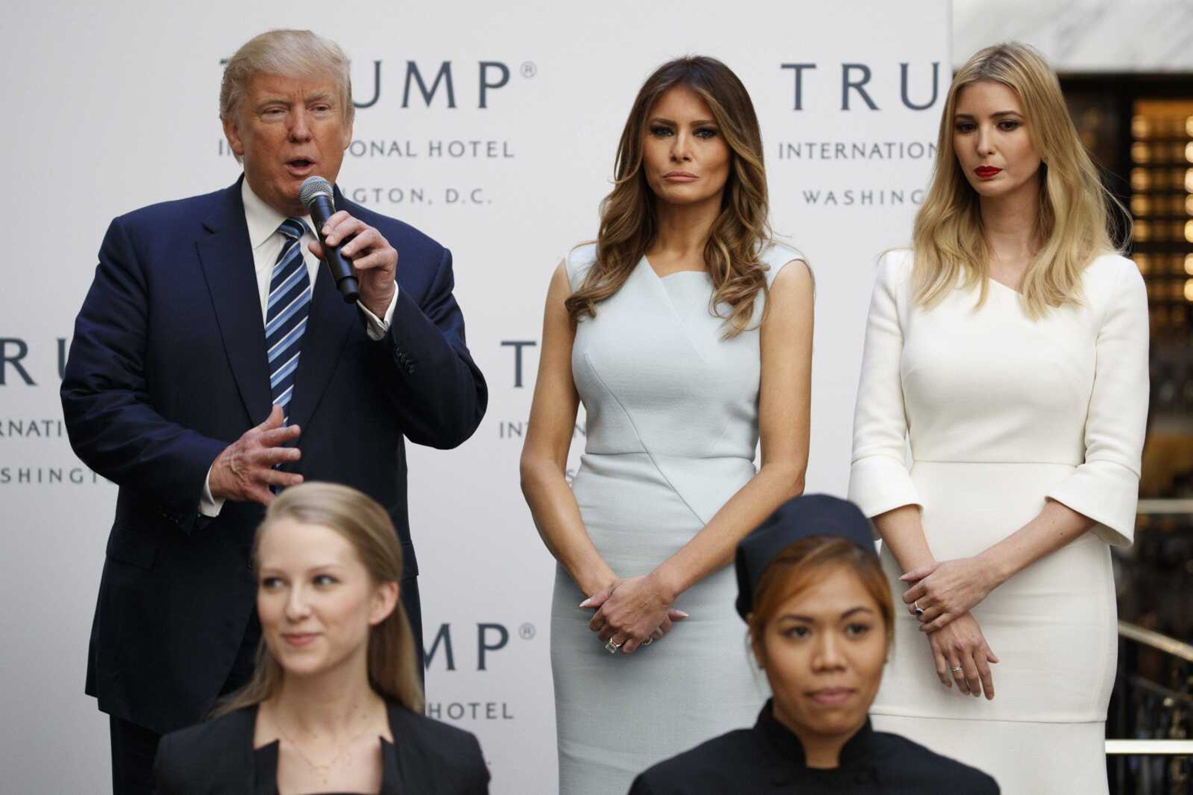 Ivanka Trump, right, and Melania Trump, center, listen as then-Republican presidential candidate Donald Trump speaks Oct. 26 during the grand opening of the Trump International Hotel-Old Post Office in Washington. People across the globe are always fascinated by what the incoming U.S. first lady is wearing to the inauguration. This time, as never before, the question is interlaced with politics, as designers have grappled publicly with the question of whether they would dress Melania Trump. Questions also have been raised about Ivanka Trump and her own label.