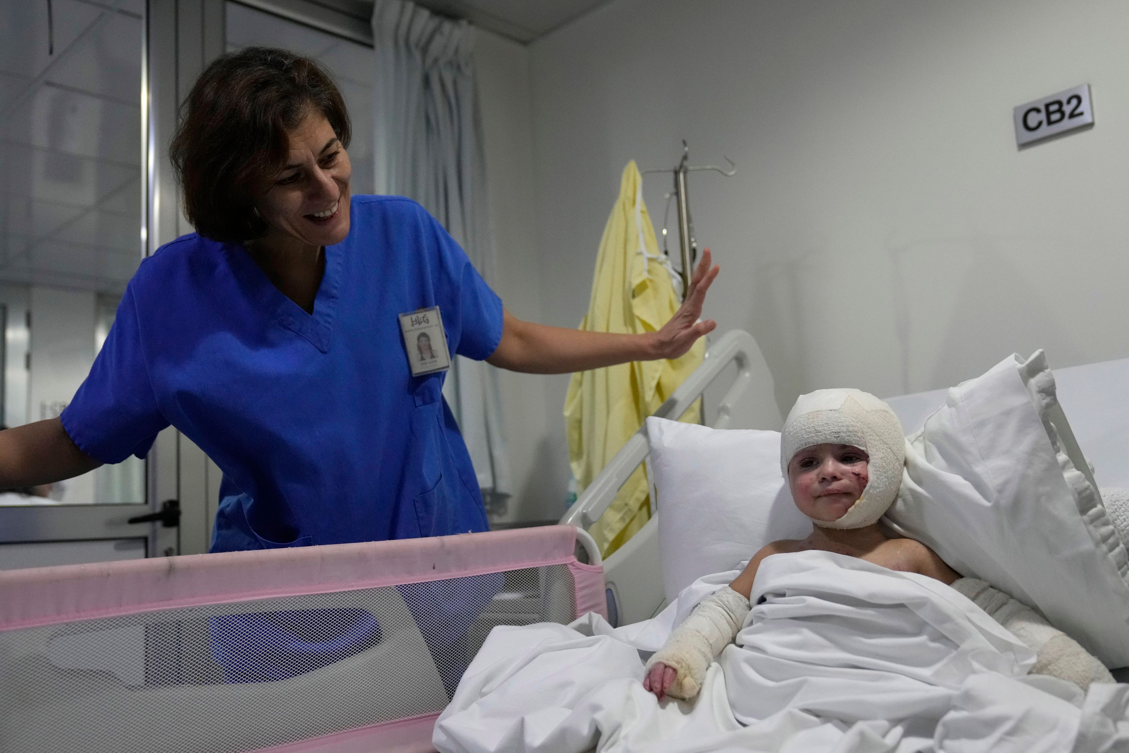 A nurse stands next of Ivana Skakye, 2, a Lebanese girl who is suffering from third-degree burns over 40 percent of her body following an Israeli airstrike last September near their home in Deir Qanoun al Nahr a village in south Lebanon, as she lies on a bed at the Geitaoui hospital where she is receiving treatment, in Beirut, Lebanon, Tuesday, Oct. 29, 2024. (AP Photo/Hussein Malla)