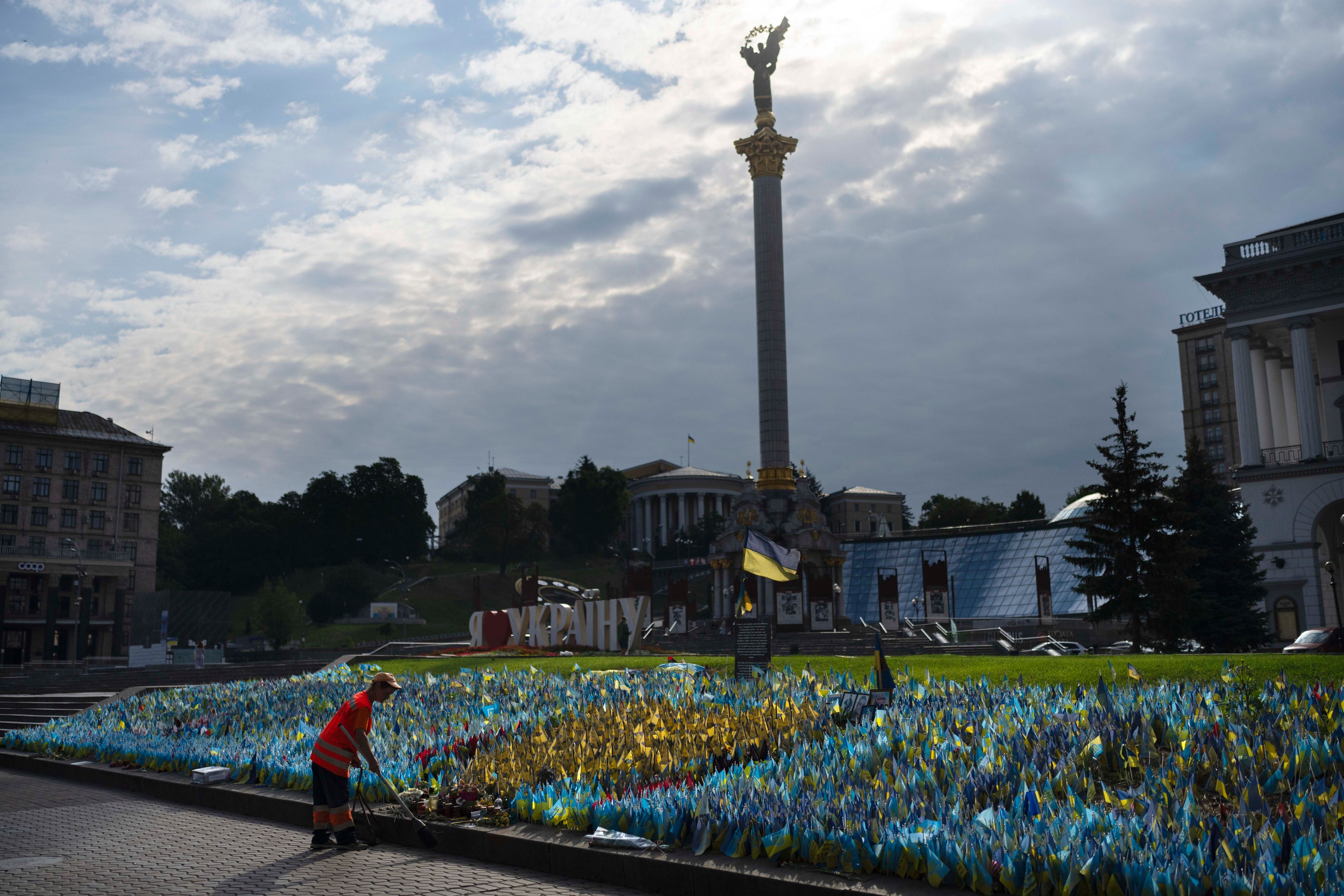 A cleaner sweeps a sidewalk in front of a memorial site honoring people killed in the war in Independence Square in Kyiv, Ukraine, Monday, July 3, 2023. (AP Photo/Jae C. Hong)