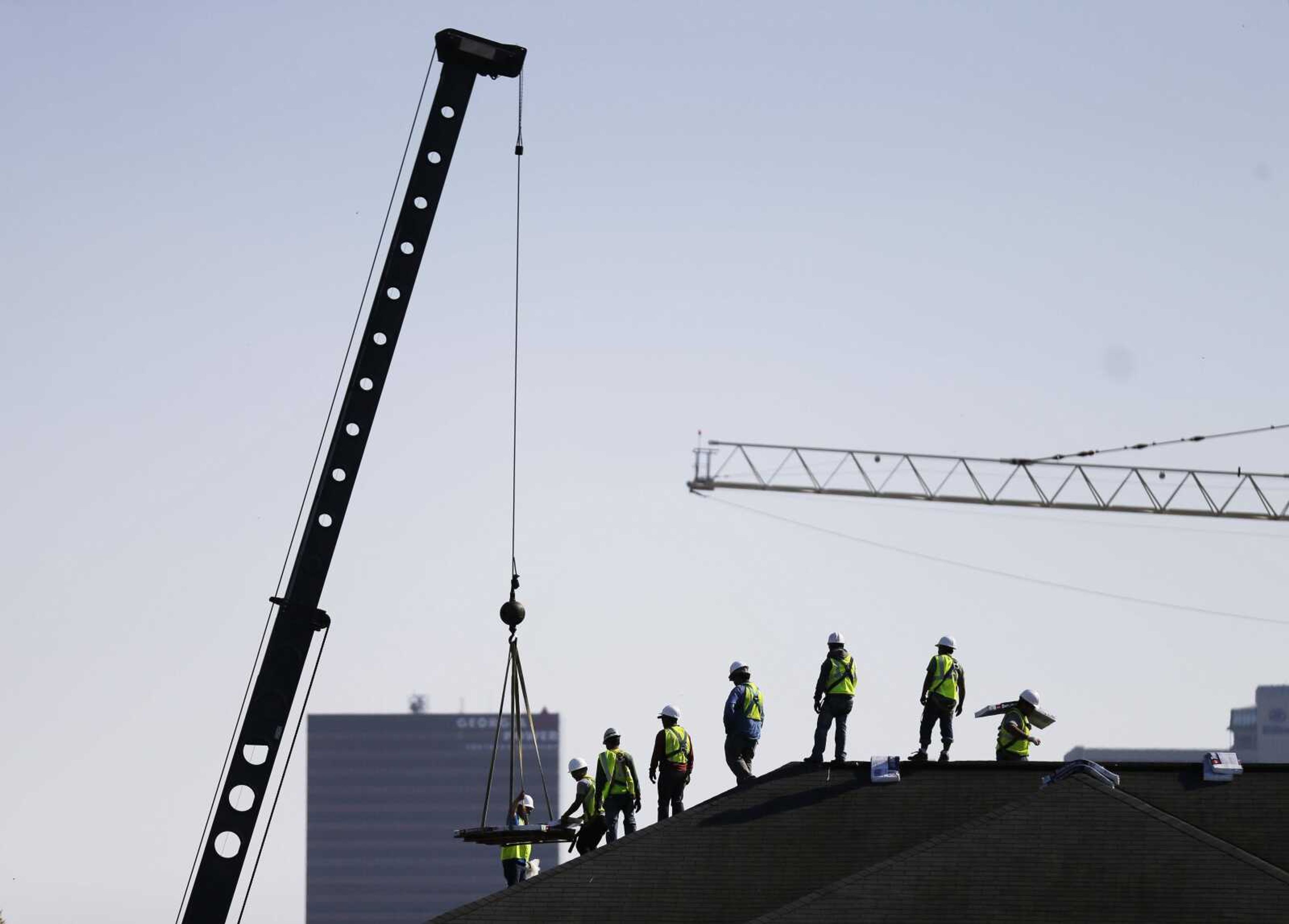 Construction workers unload supplies off a hoisted pallet on a rooftop in Atlanta.