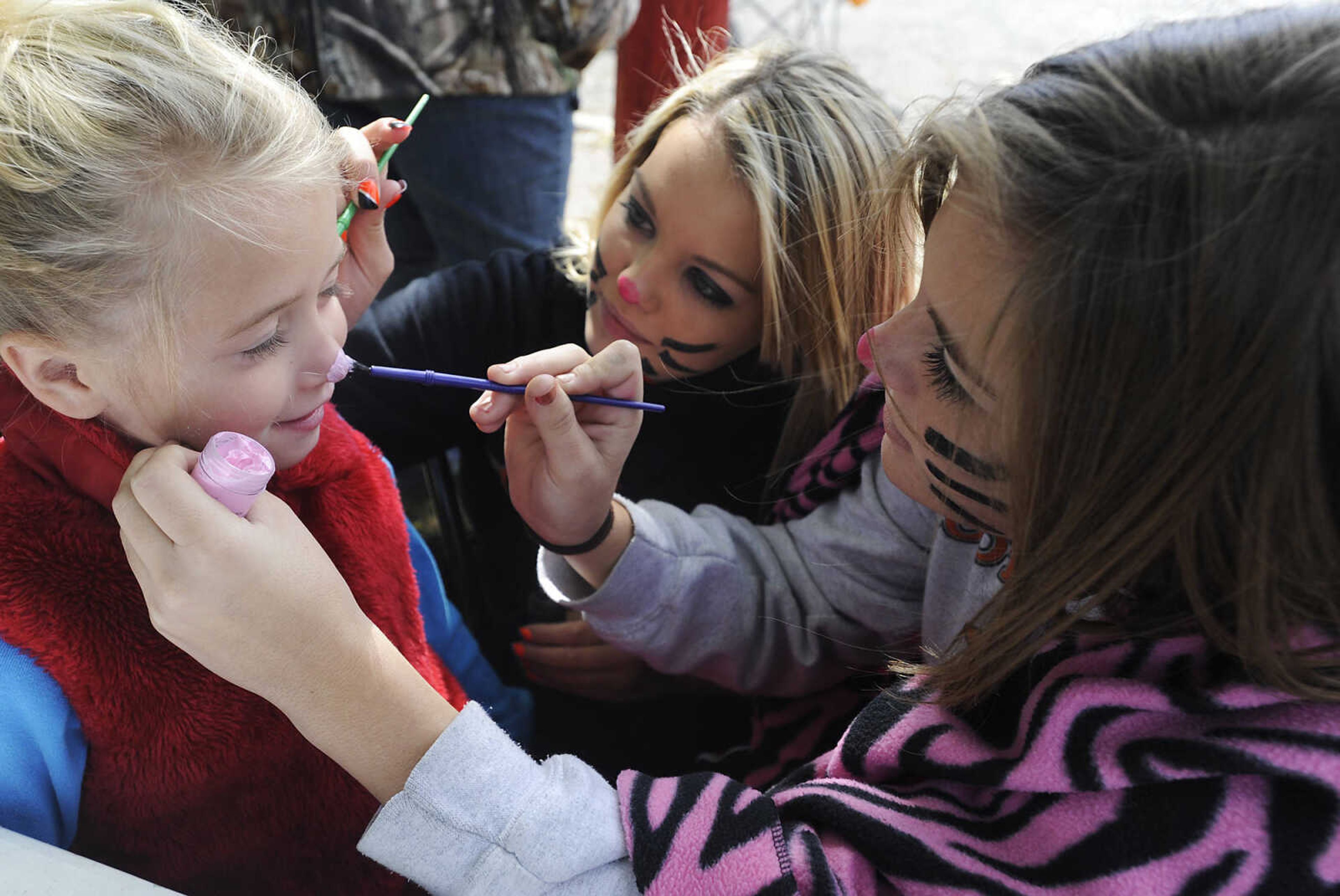 Taylor Van Pool, 15, right, and Katlyn Masters, 15, give Tabatha Walker cat whiskers and a cat nose during the Morley Fall Festival Saturday, October 6, in Morley. The Van Pool and Masters were doing face painting as a fundraiser for the Scott County Central High School cheerleaders, of which both are members.