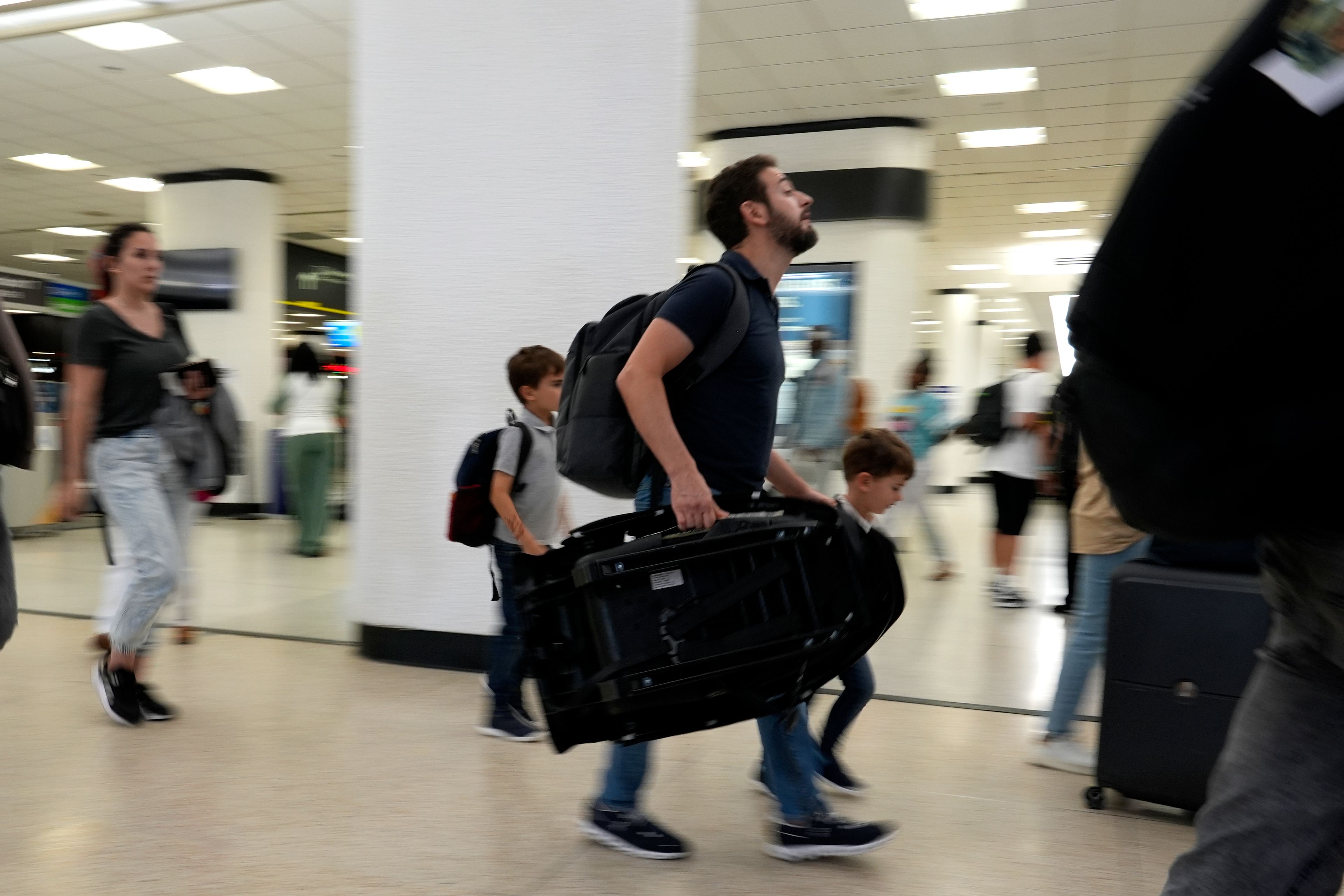 FILE - Travelers walk through the concourse at Miami International Airport on May 23, 2024, in Miami. (AP Photo/Lynne Sladky, File)