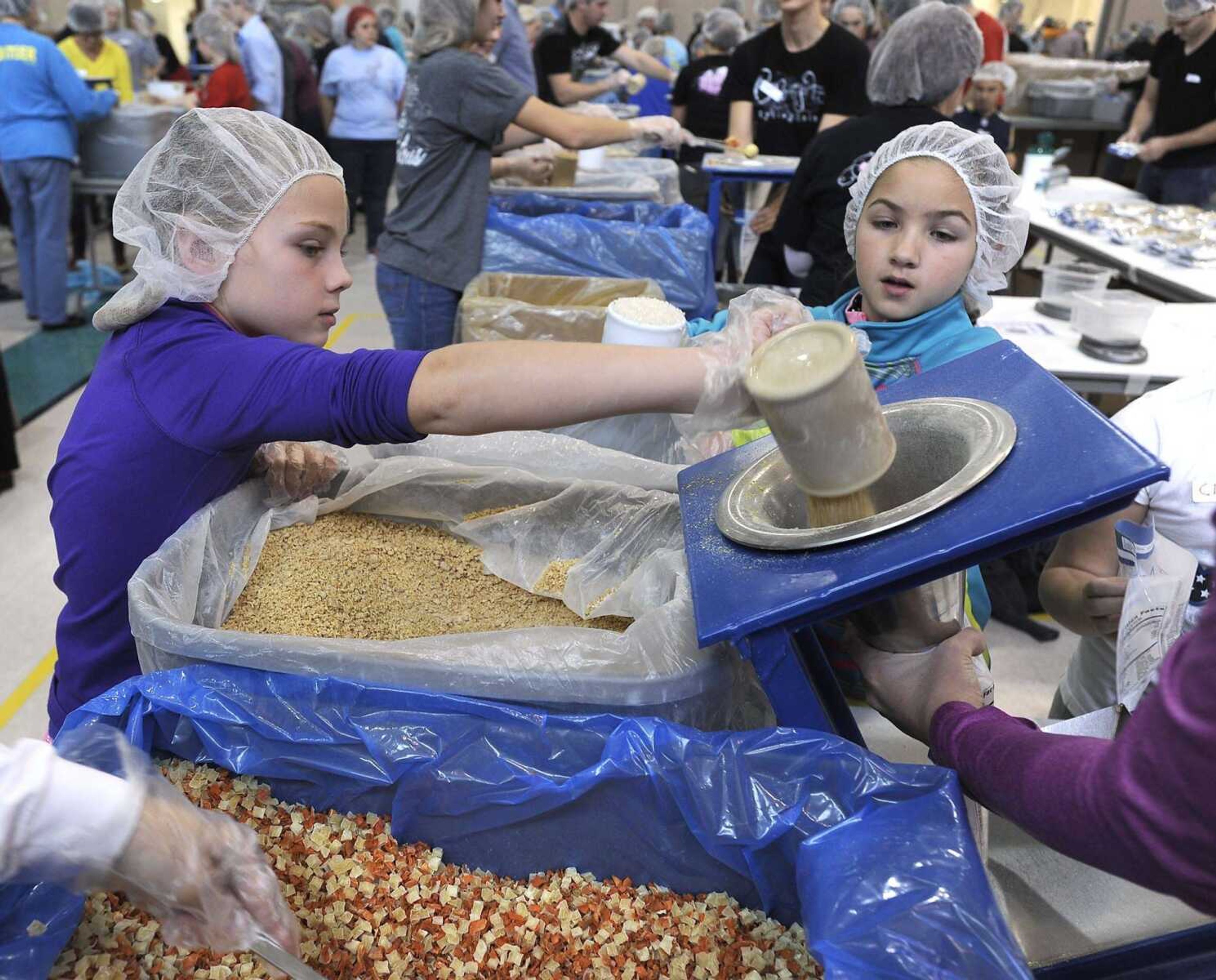 Emerson Pitts, left, pours soy as Ella Clifton waits to add rice on the MannaPack line at the Feed My Starving Children MobilePack event Dec. 7 at the Osage Centre in Cape Girardeau. (Fred Lynch)