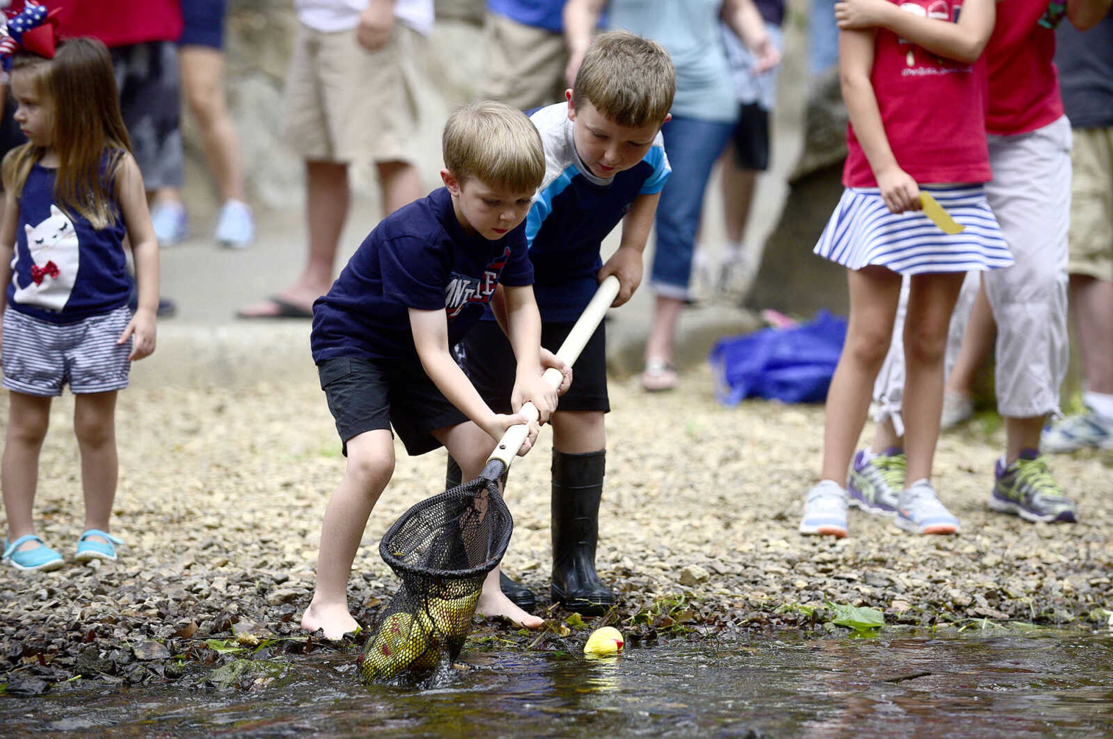 Wesley Kuehle, left, and Lawson Miller help collect ducks after the duck race in Hubble Creek during the Fourth of July celebration on Tuesday at Jackson City Park.