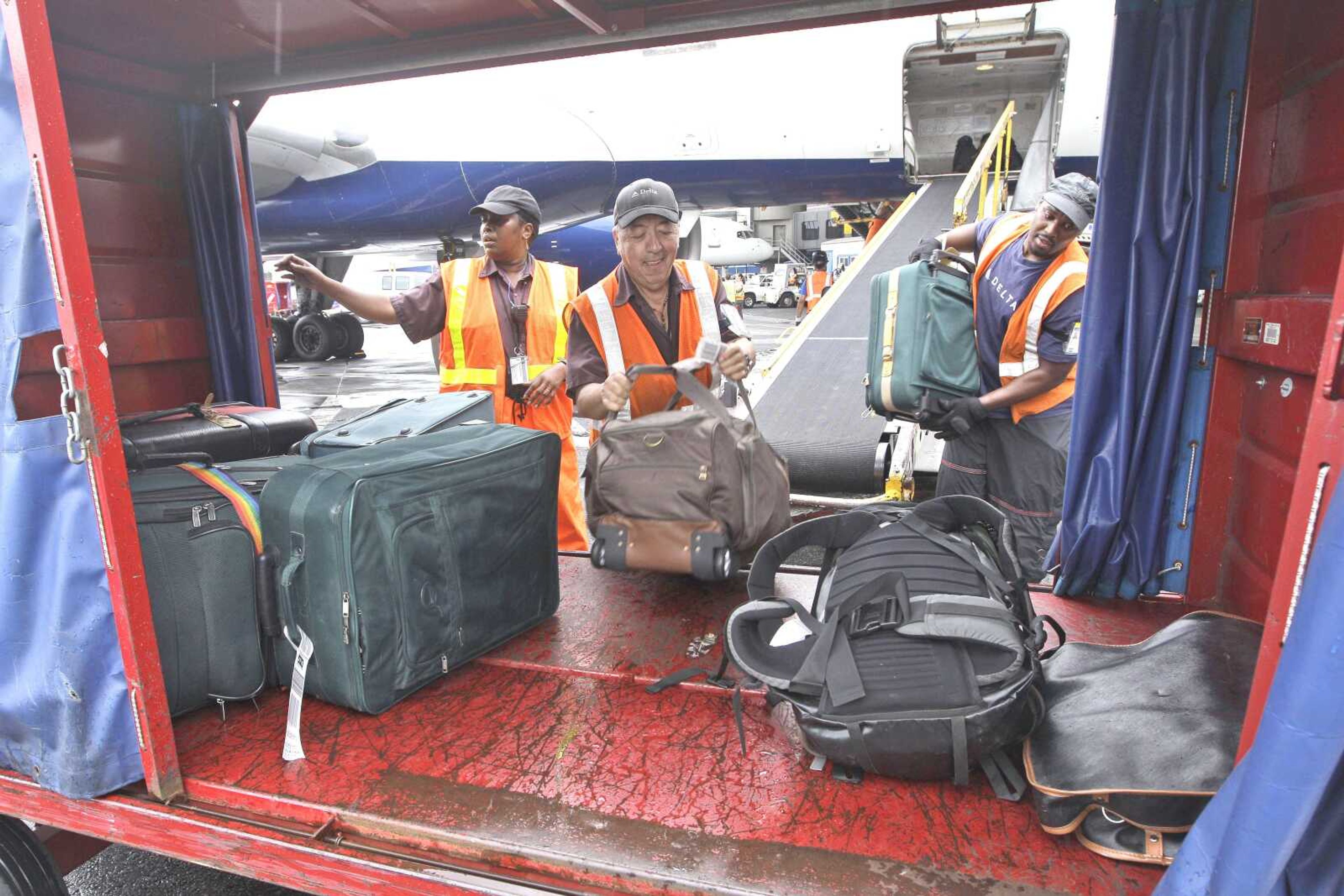 Delta Air Lines ramp agents unload bags from a flight arriving Aug. 1 at JFK International airport in New York. U.S. airlines collected more than $1.7 billion in baggage fees during the first half of the year, the largest amount ever collected in that six-month period. Delta Air Lines Inc. once again claimed the title as the airline collecting the most in baggage fees: nearly $430 million from January through June. (Associated Press file)