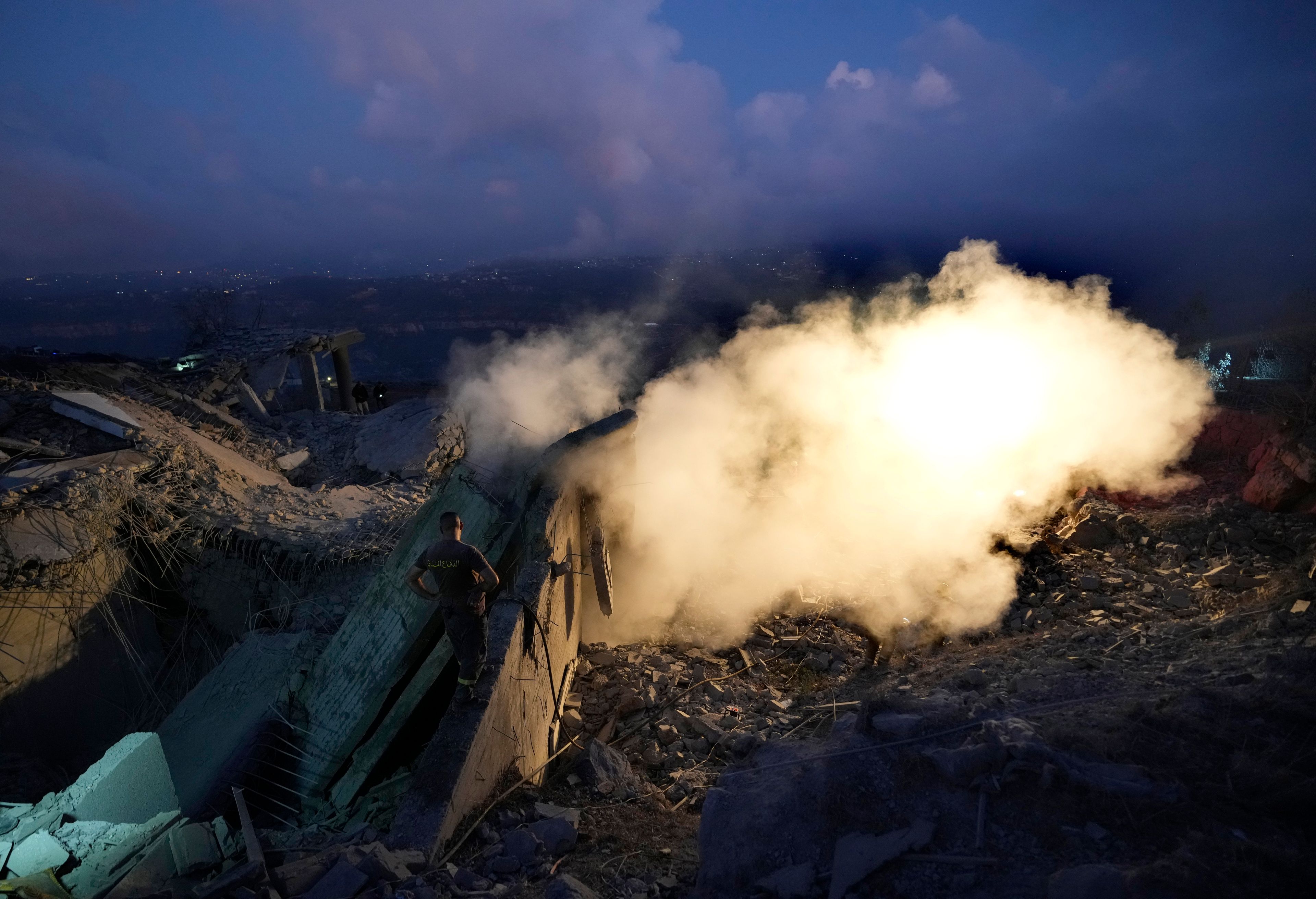 A rescue worker searches for victims as smoke rises from a house hit in an Israeli airstrike in Baalchmay village east of Beirut, Lebanon, Tuesday, Nov. 12, 2024. (AP Photo/Hassan Ammar)