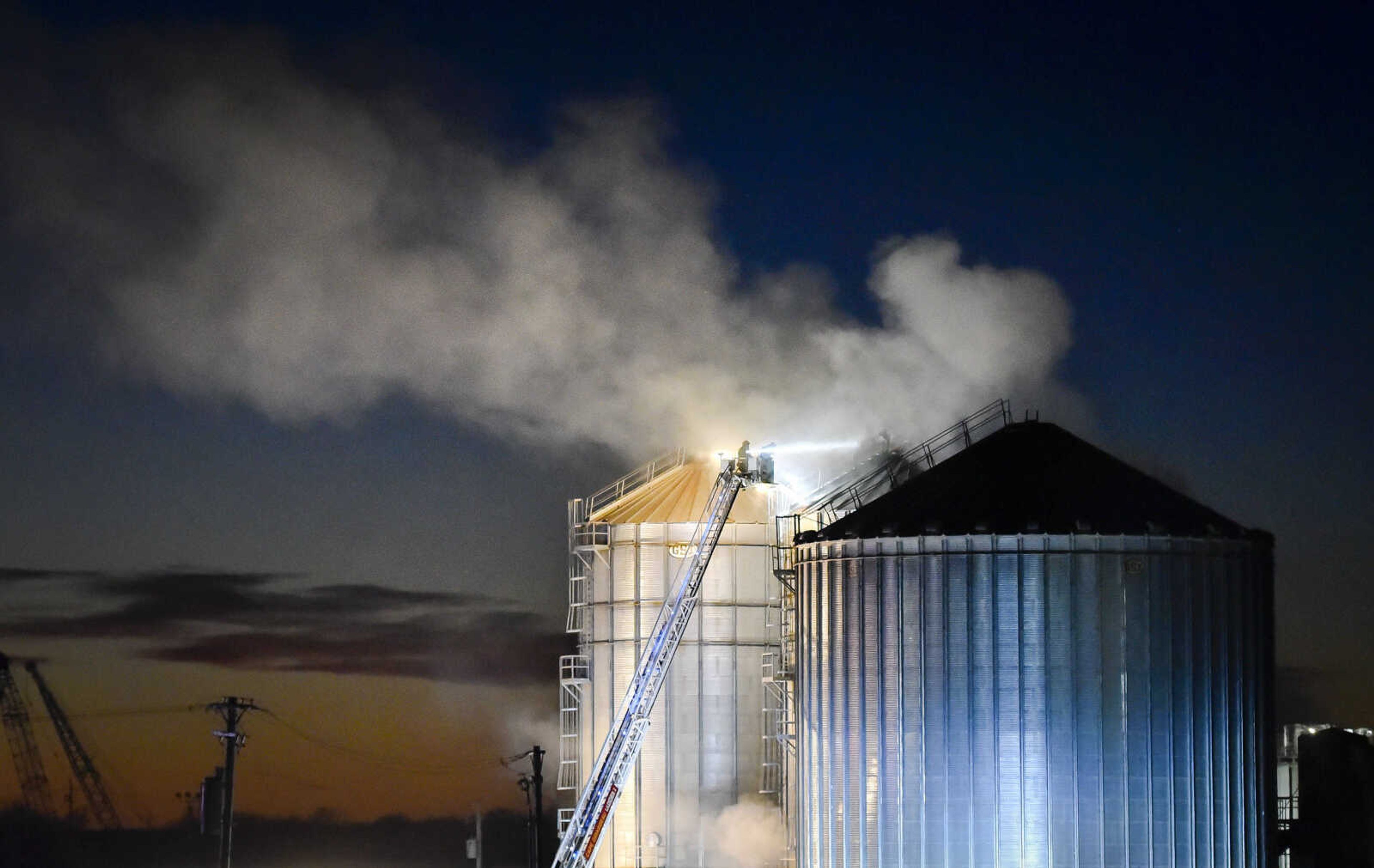 Smoke billows out of a grain silo as firefighters deploy a ladder truck to contain a working fire Tuesday, Nov. 19, 2019, at Midwest Grain and Barge in Scott City, Missouri. It was the second fire at the location in two weeks.