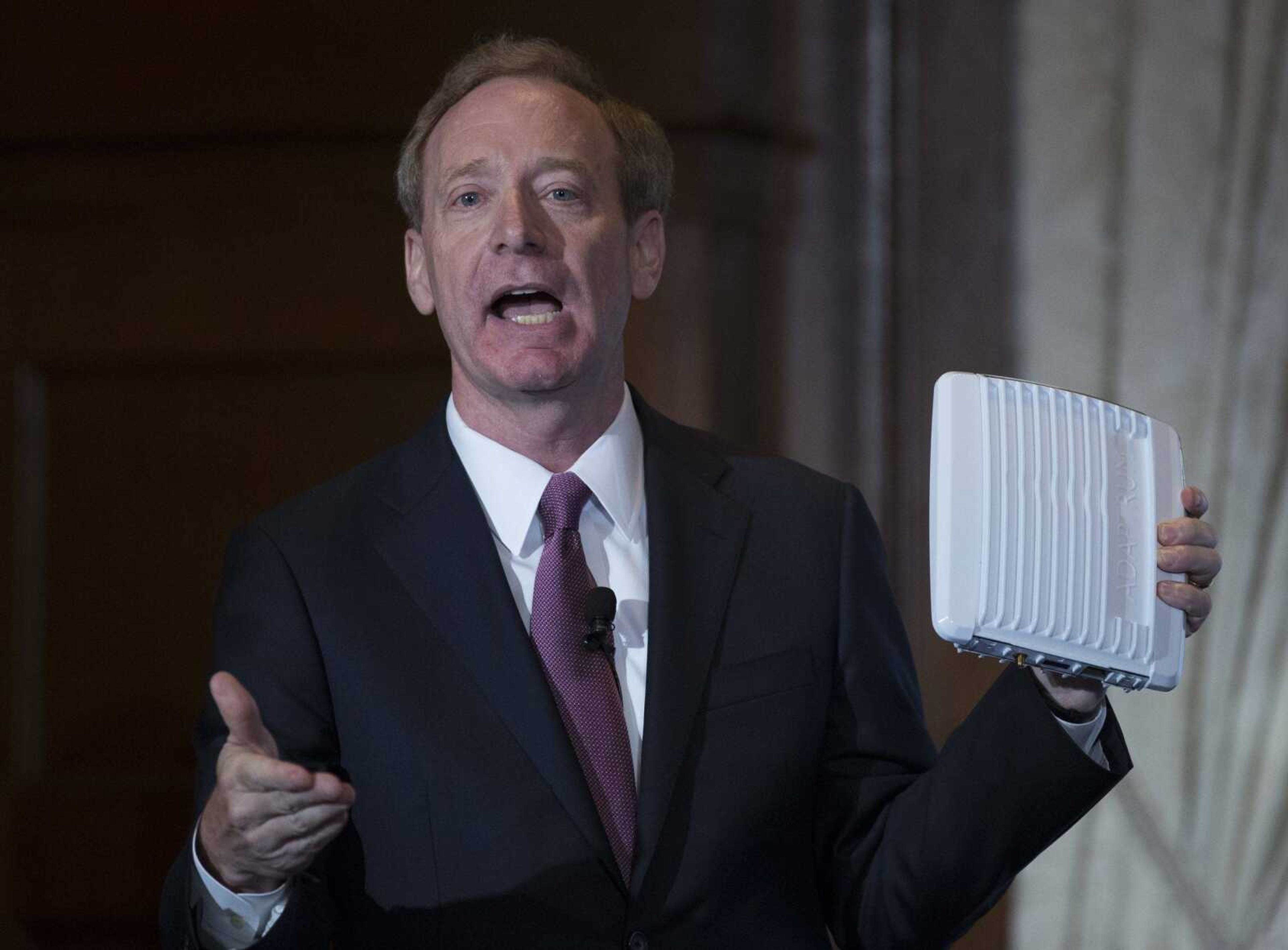 Microsoft president and chief legal officer Brad Smith holds up an ACRS2 device by ADAPTRUM used in TV White Space communications as he speaks Tuesday in Washington about Microsoft's project to bring broadband internet access to rural parts of the U.S.