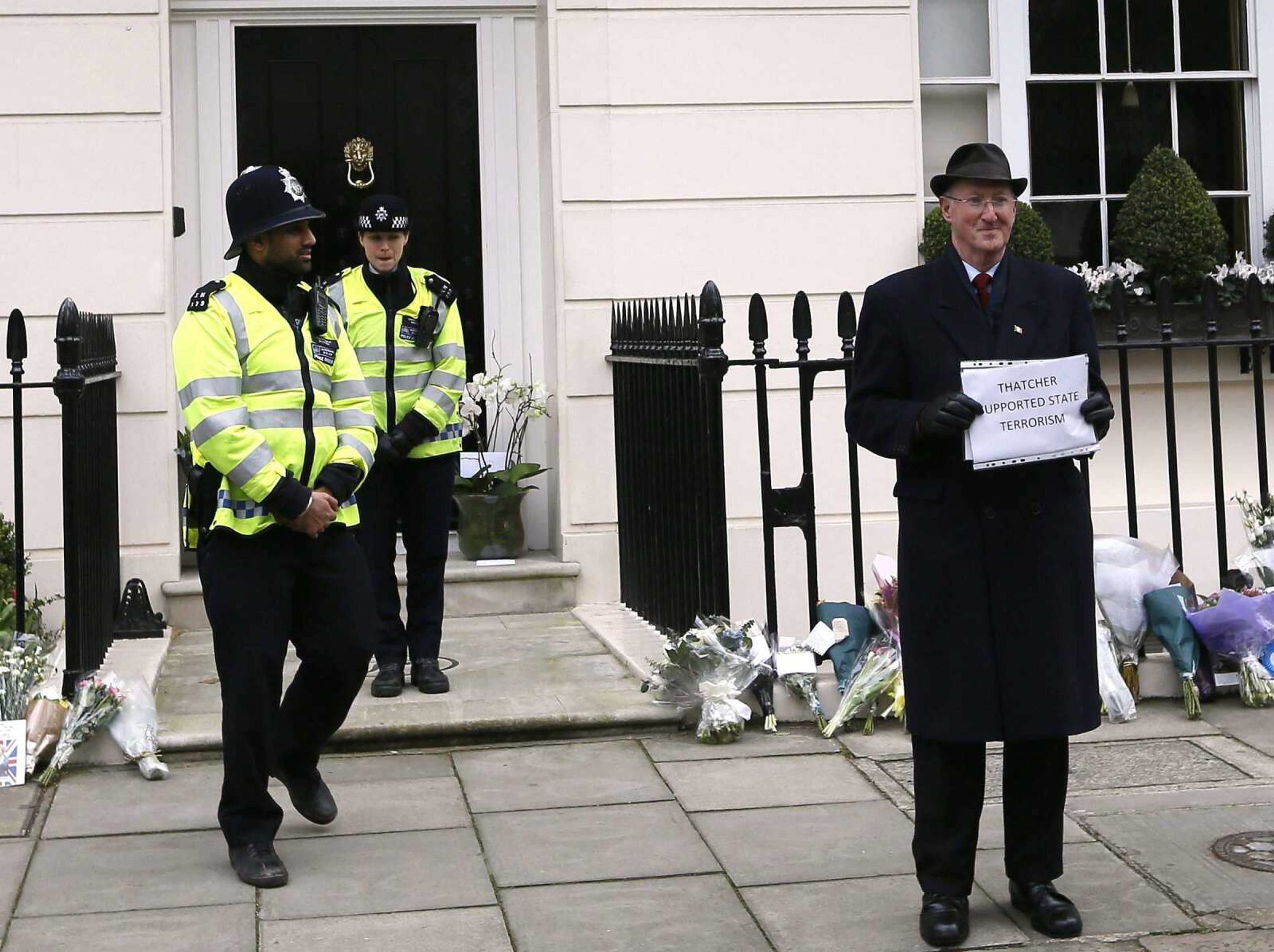 A man holds up a protest banner outside former British Prime Minister Baroness Thatcher&#8217;s home Tuesday in London. (Kirsty Wigglesworth ~ Associated Press)