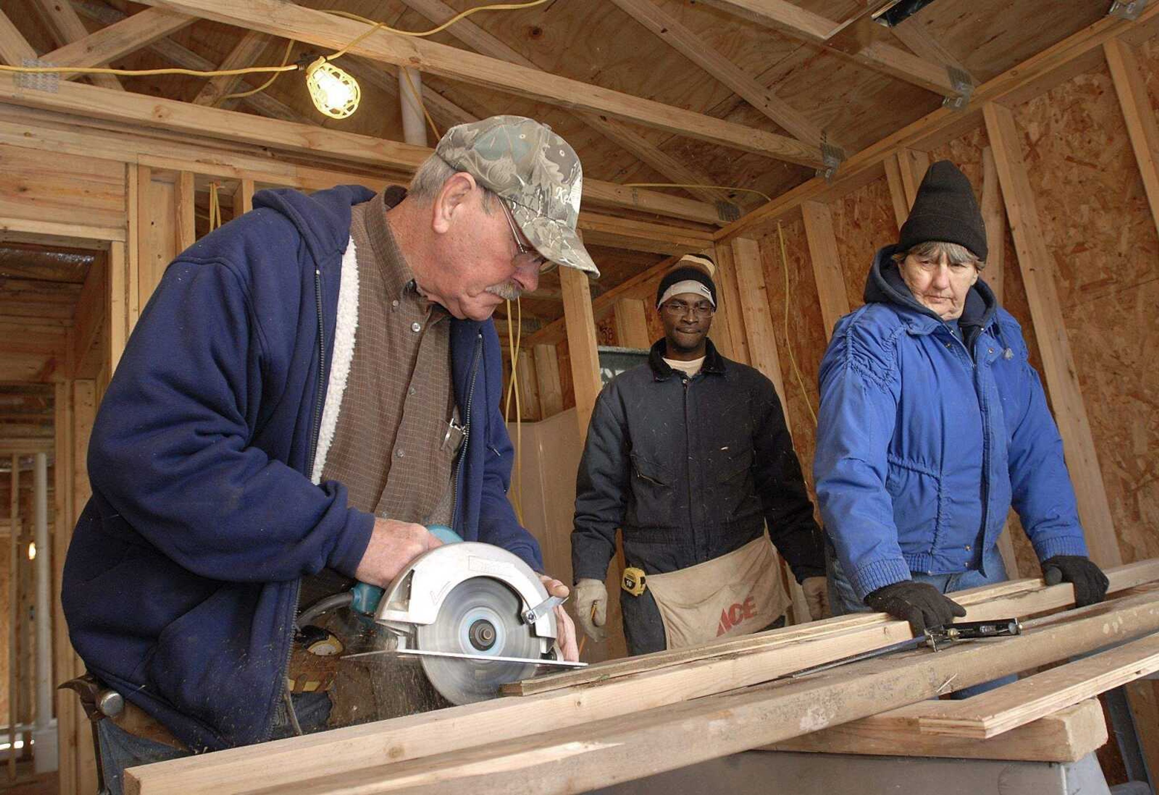 FRED LYNCH ~ flynch@semissourian.com
Marshall Heisler saws a board as Brian Murray and Margaret Blackstone watch in a Habitat for Humanity house Saturday in Cape Girardeau.