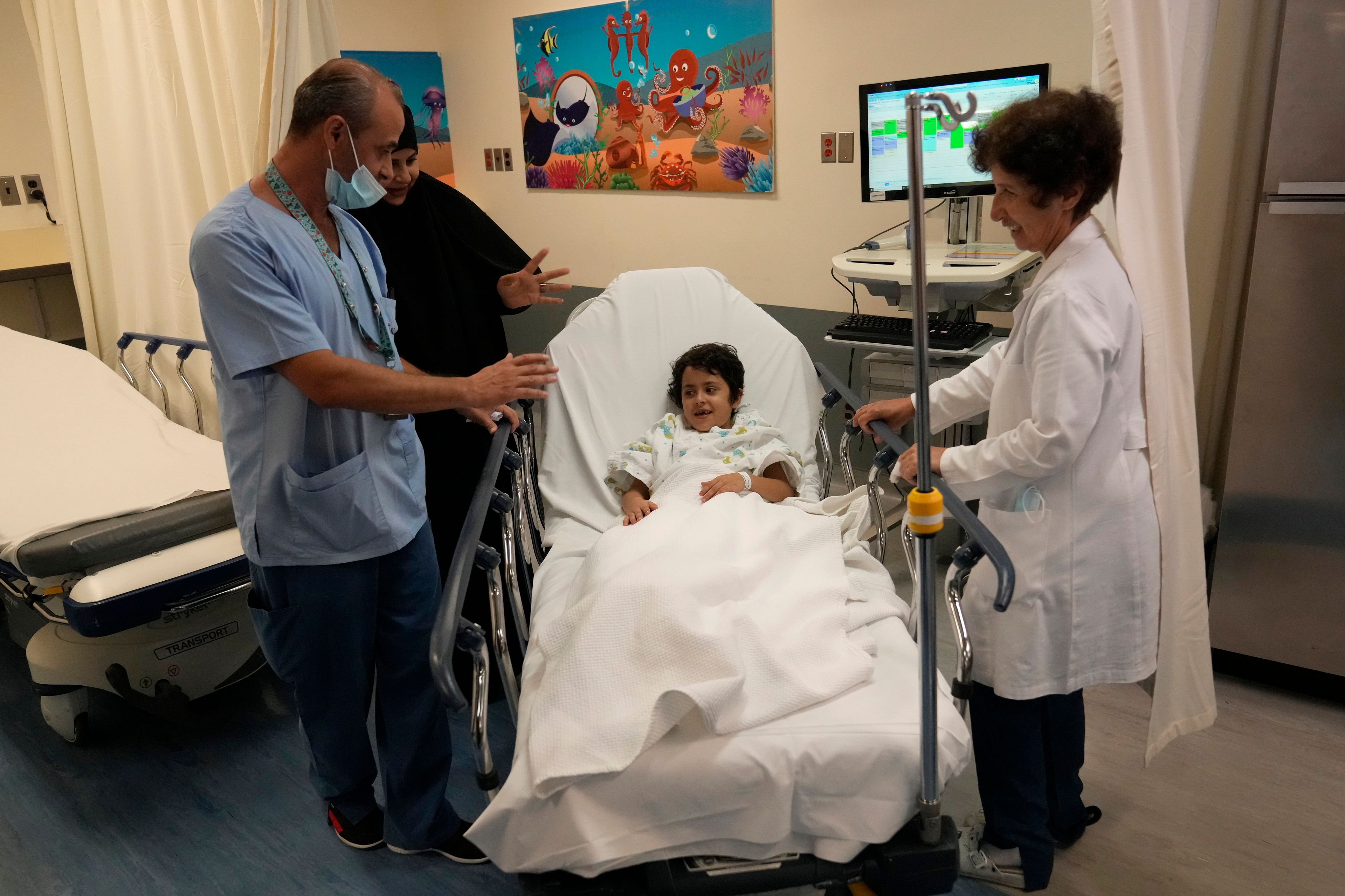 Halima Abou Yassine, 7, who was brought to Lebanon from Gaza for treatment after an Israeli strike left her near death with a gaping wound in her skull, lies on a hospital bed as she is moved by nurses to the operating room for surgery at the American University of Beirut Medical Center in Beirut, Lebanon, Monday, July 15, 2024. (AP Photo/Hussein Malla)