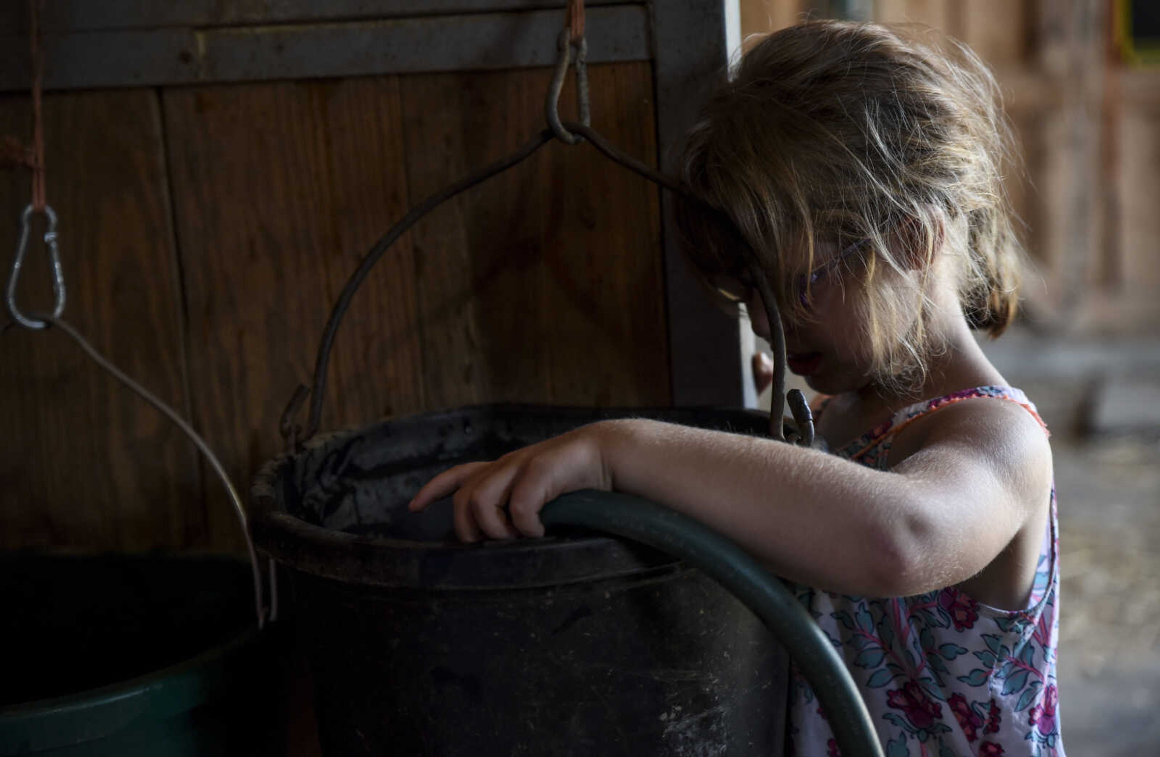 Lindyn Davenport, 6, helps fill a bucket full of fresh drinking water after learning how to clean a horse stall during a summer camp session at Mississippi Valley Therapeutic Horsemanship Friday, June 8, 2018 in Oak Ridge.