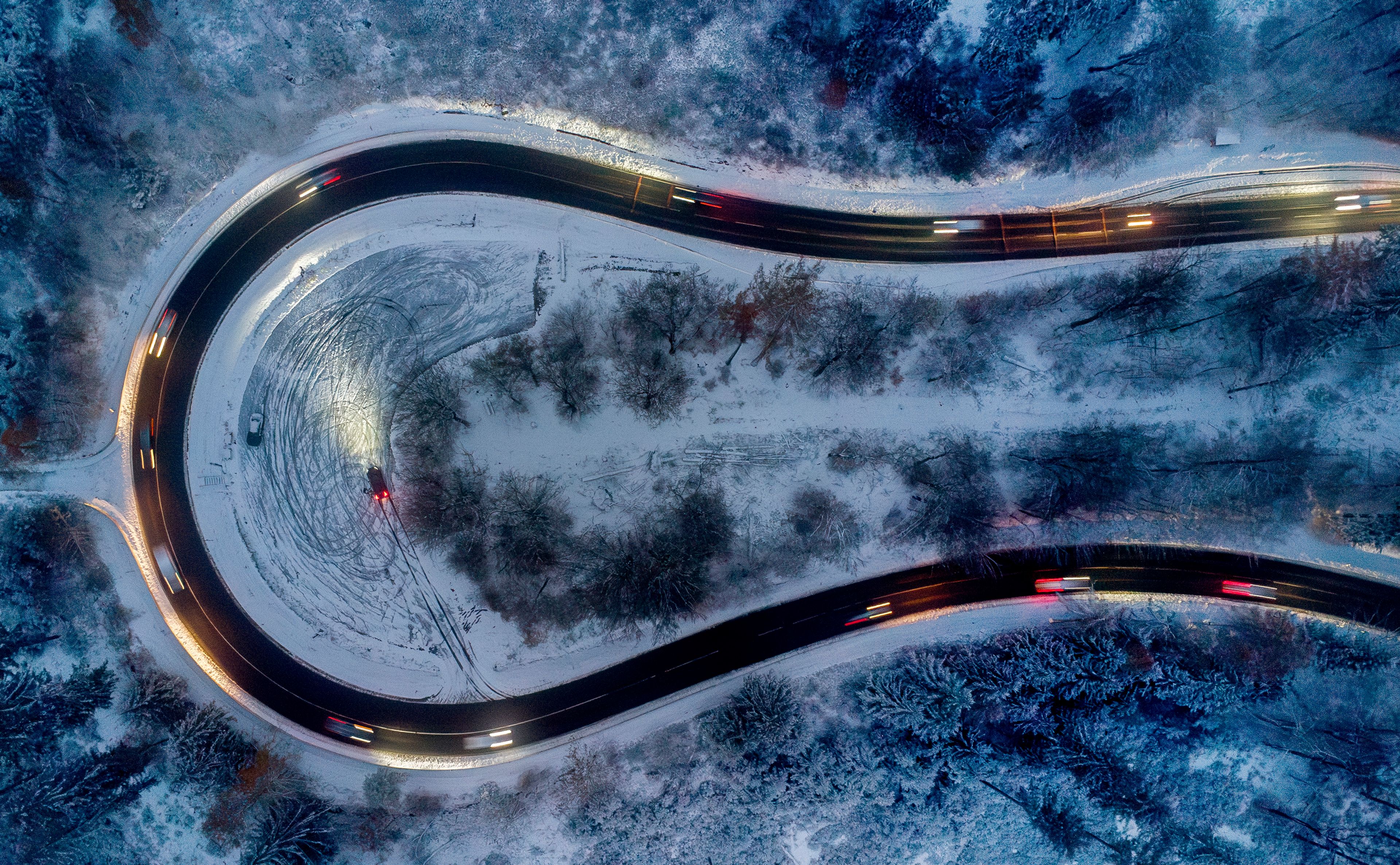 Cars drive through curve in a forest of the Taunus region near Frankfurt, Germany, after snow falls during the night on Thursday, Nov. 21, 2024. (AP Photo/Michael Probst)