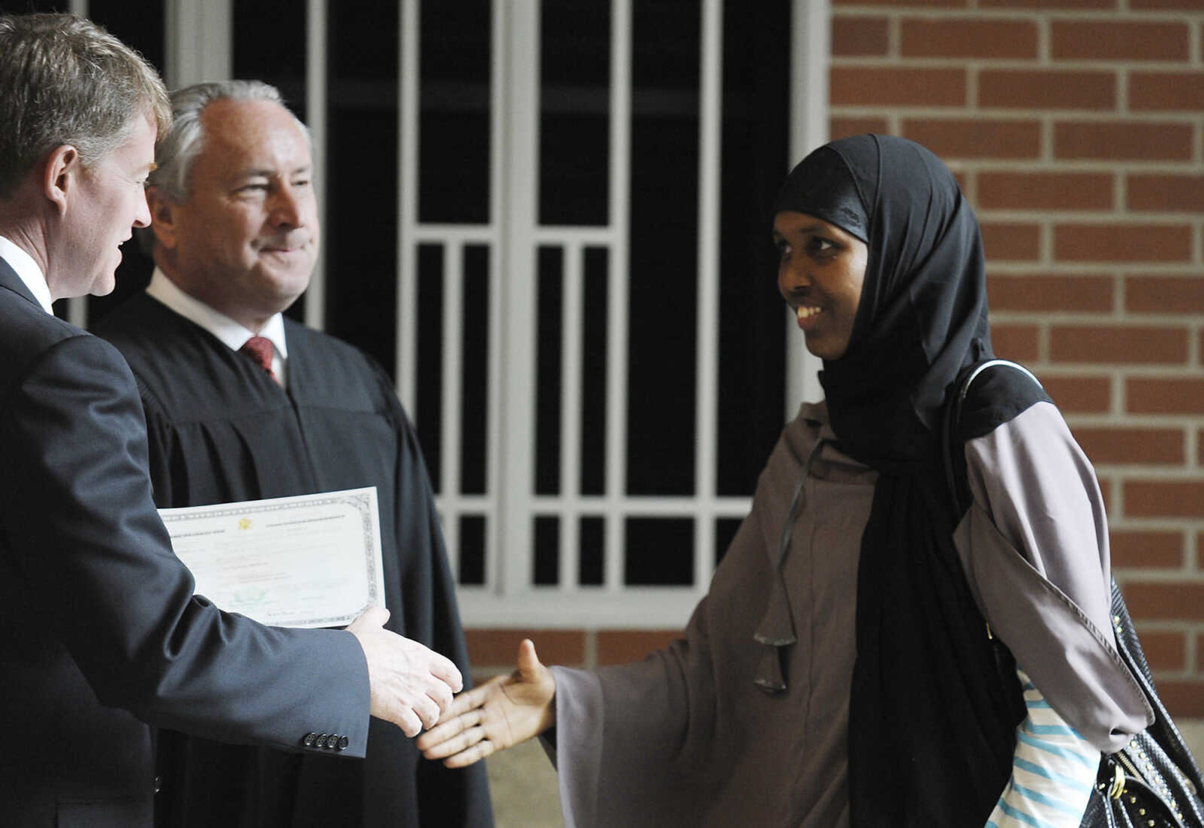 Fadumo Fakat, who immigrated to the U.S. from Somalia, shakes hands with Missouri Attorney General Chris Koster, left, and U.S. District Court Judge Stephen N. Limbaugh Jr. after a naturalization ceremony Wednesday, May 1, at the Rush H. Limbaugh Sr. U.S. Courthouse in Cape Girardeau. Limbaugh administered the oath to 29 people from 11 countries, making them U.S. citizens, during the ceremony.