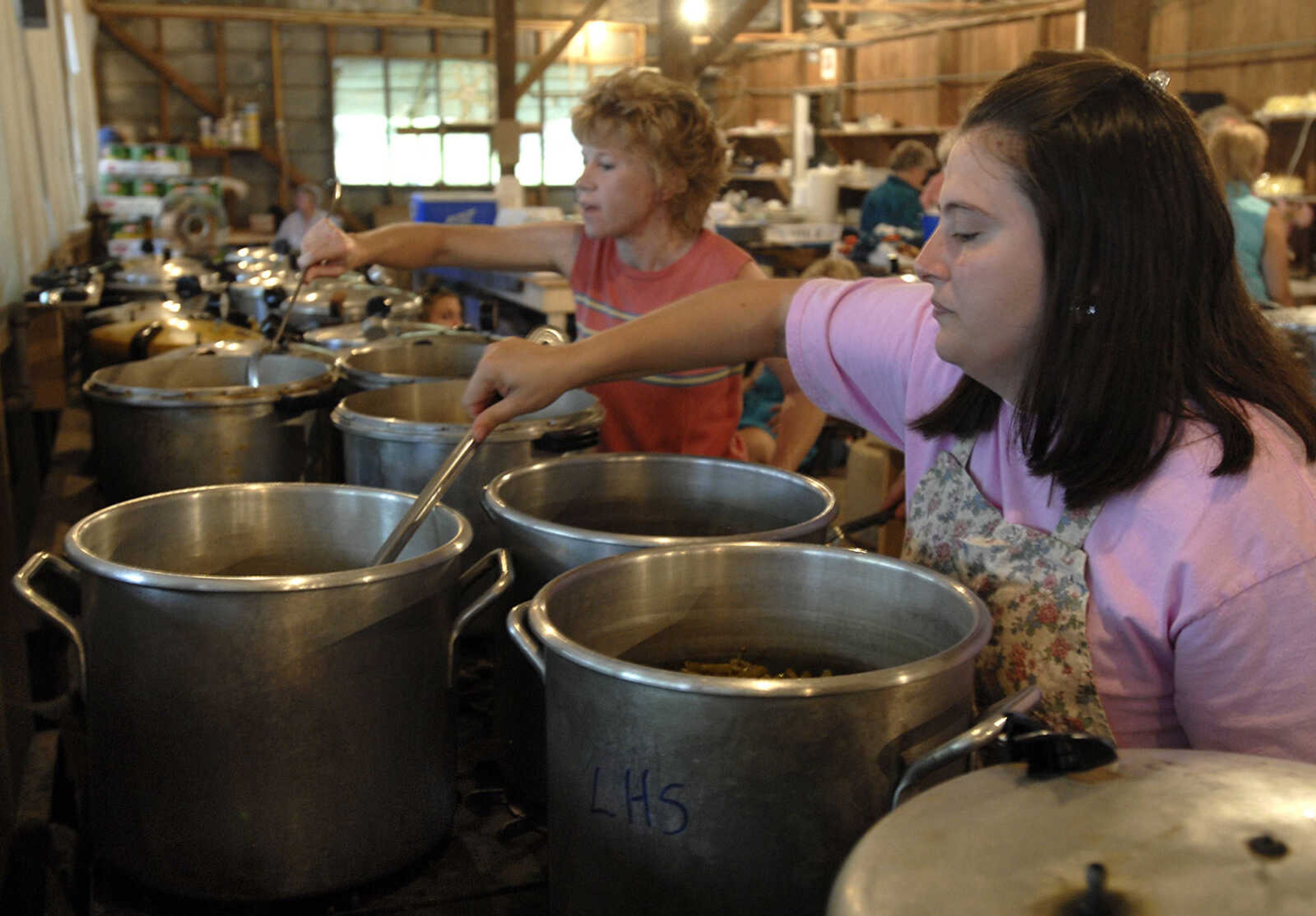 Heather Elfrink, right, stirs green beans while Peggy Nenninger checks on the beef for the Leopold Picnic.