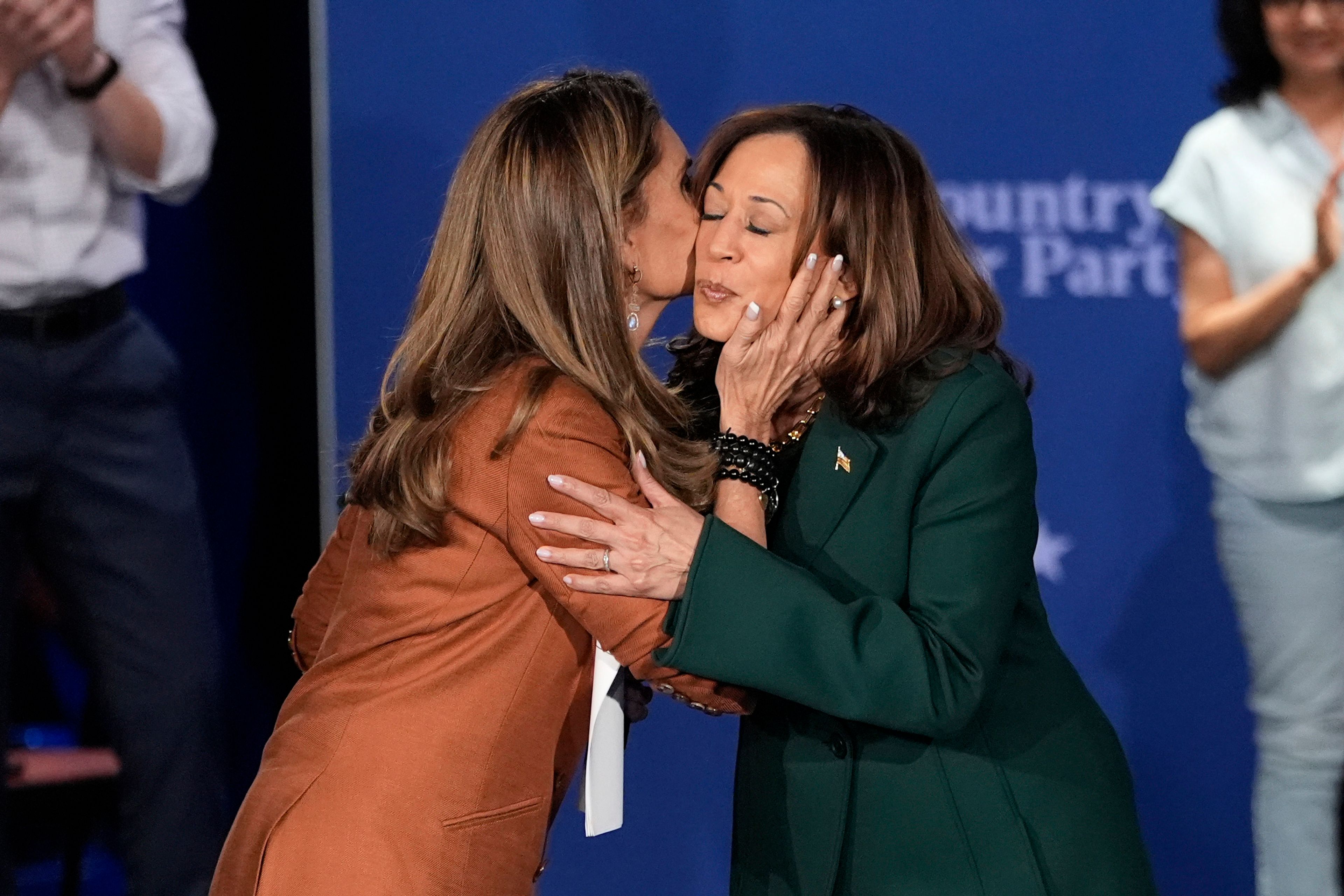 Moderator Maria Shriver, left, kisses Democratic presidential nominee Vice President Kamala Harris at the start of a town hall at the Royal Oak Theatre in Royal Oak, Mich., Monday, Oct. 21, 2024. (AP Photo/Carlos Osorio)