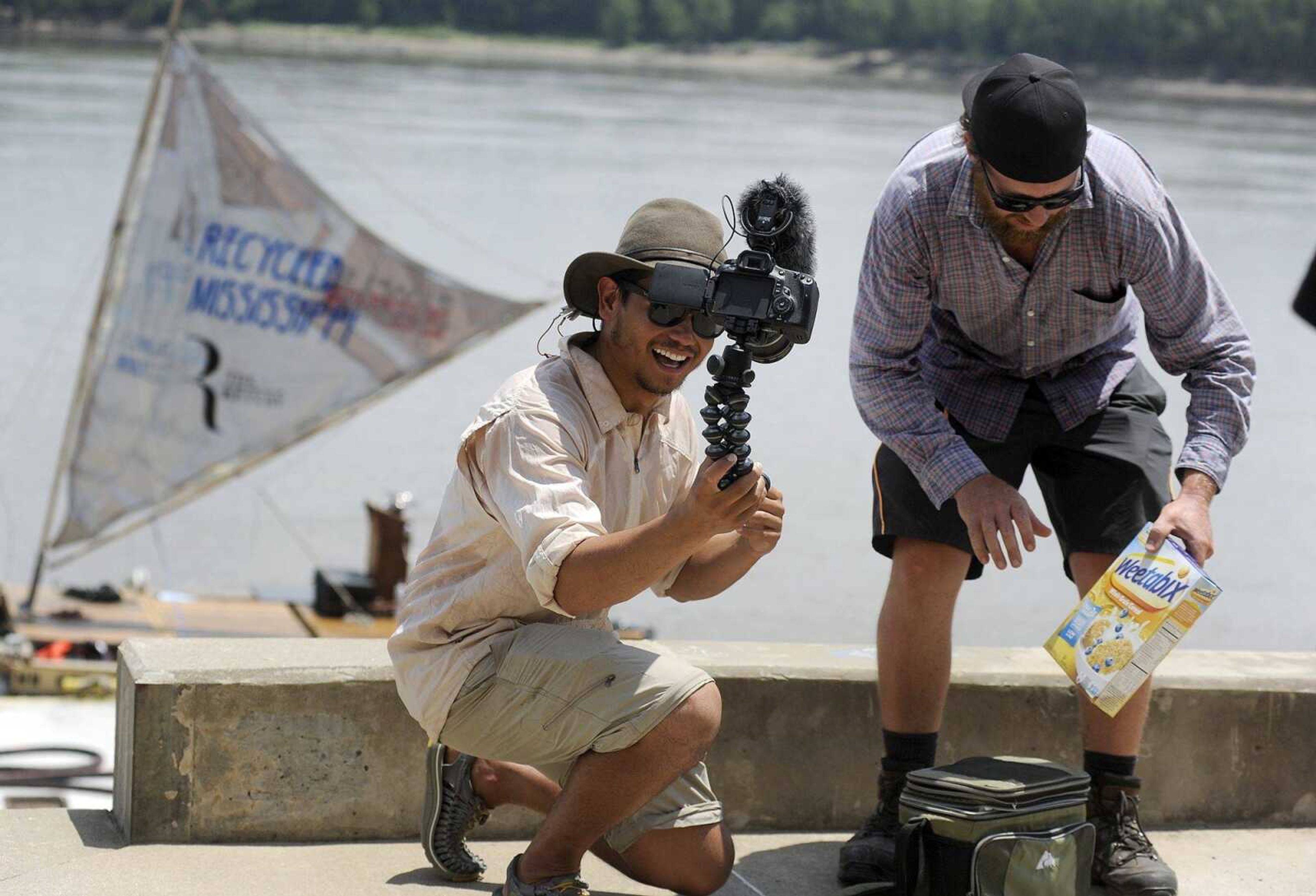 Dan Cullum, left, shoots a video blog after Frankie Gaul brought him fresh milk from his farm and a box of Weetabix on Tuesday at the riverwalk in downtown Cape Girardeau. Cullum, a New Zealand resident, is traveling with a group of five other guys down the Mississippi River on a boat made out of recycled materials. Cullum was so excited when Gaul, also a New Zealand native, brought the cereal and fresh milk, a traditional breakfast dish in New Zealand.