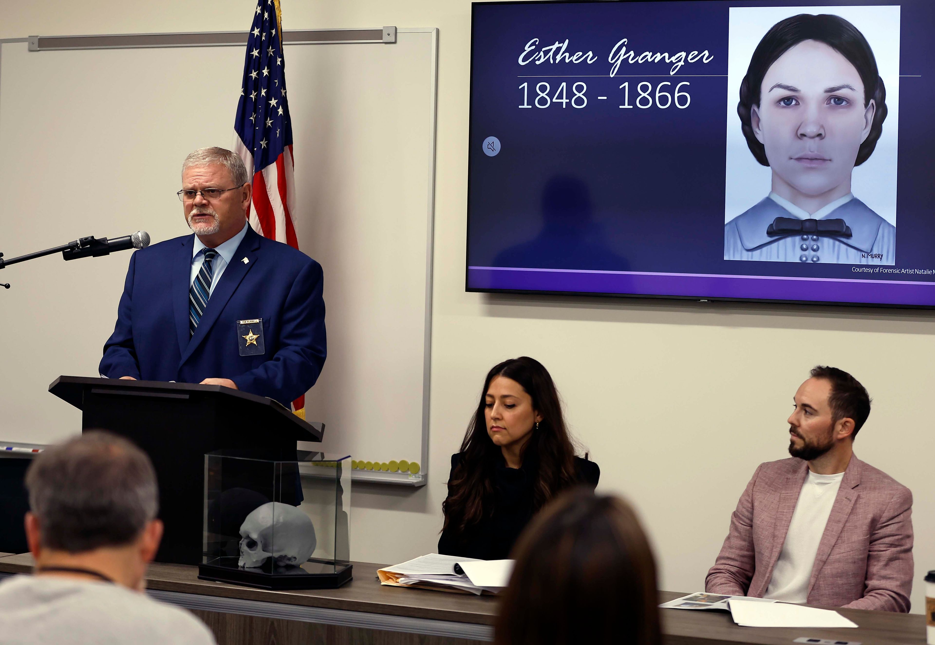 Kane County Coroner Rob Russell is pictured with an artist's rendering of the likeness of Esther Granger as he speaks during a press conference Thursday, Oct. 24, 2024 in St. Charles, Ill. Investigators have determined that a skull discovered in the wall of an Illinois home in 1978 was that of an Indiana teenager who died more than 150 years ago, authorities announced Thursday. (Brian Hill/Daily Herald via AP)