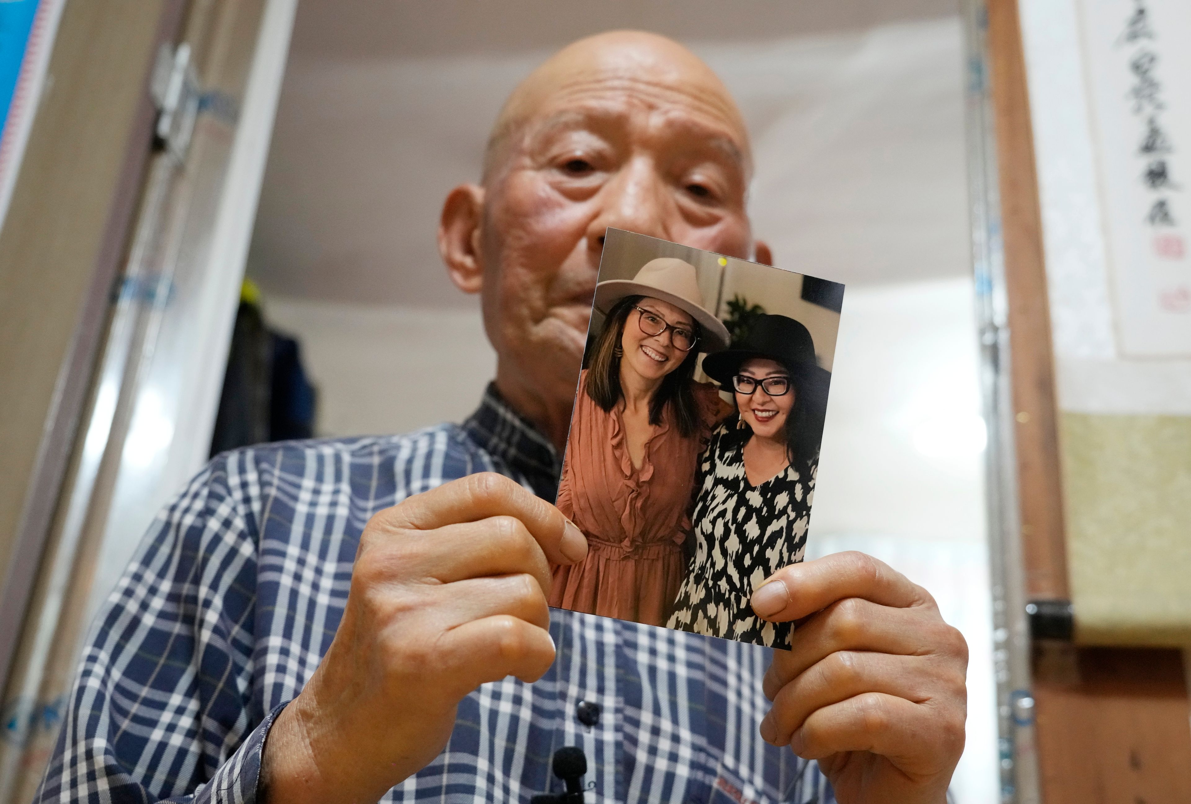 Park Jong-kyun holds a photo showing his twin daughters, Dee Iraca, left, and Becca Webster, at his house on Jeju Island, South Korea, Wednesday, Feb. 21, 2024. His twins were born at a time when he and his late wife were struggling financially to raise three sons. His wife needed an emergency C-section, which the couple couldn't afford. The hospital persuaded them to give away the twins to relieve the financial burden and toll on his wife's health, Park says. (AP Photo/Ahn Young-joon)