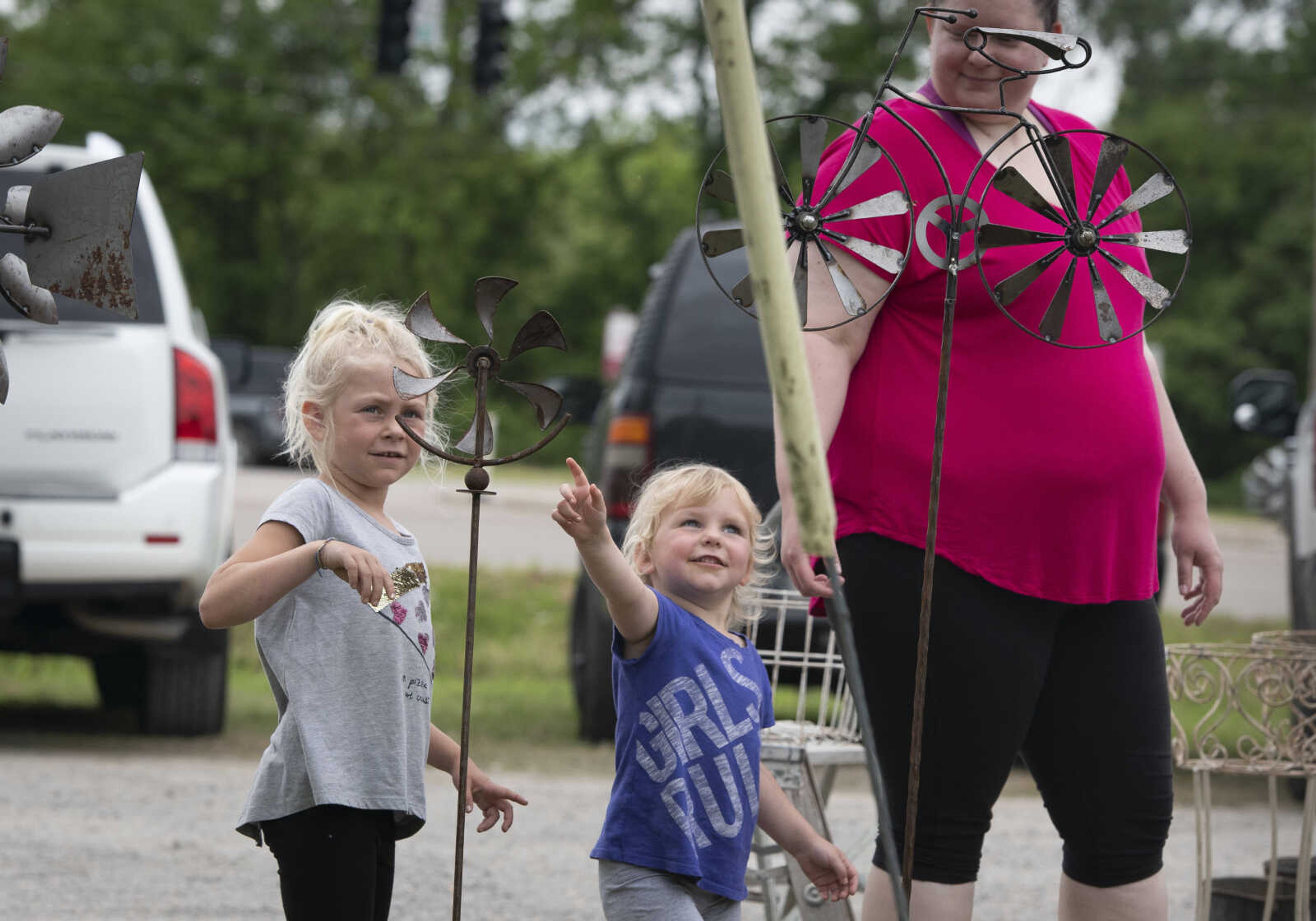 Violet Nelson (middle), 3, of Springfield, Missouri, points toward a windmill decoration near her sister Emma Nelson, 5, also of Springfield, and their aunt Micki Wooten of Chaffee, Missouri, at a sale in Dutchtown during the 100-Mile Yard Sale on Saturday, May 23, 2020, along Highway 25.&nbsp;