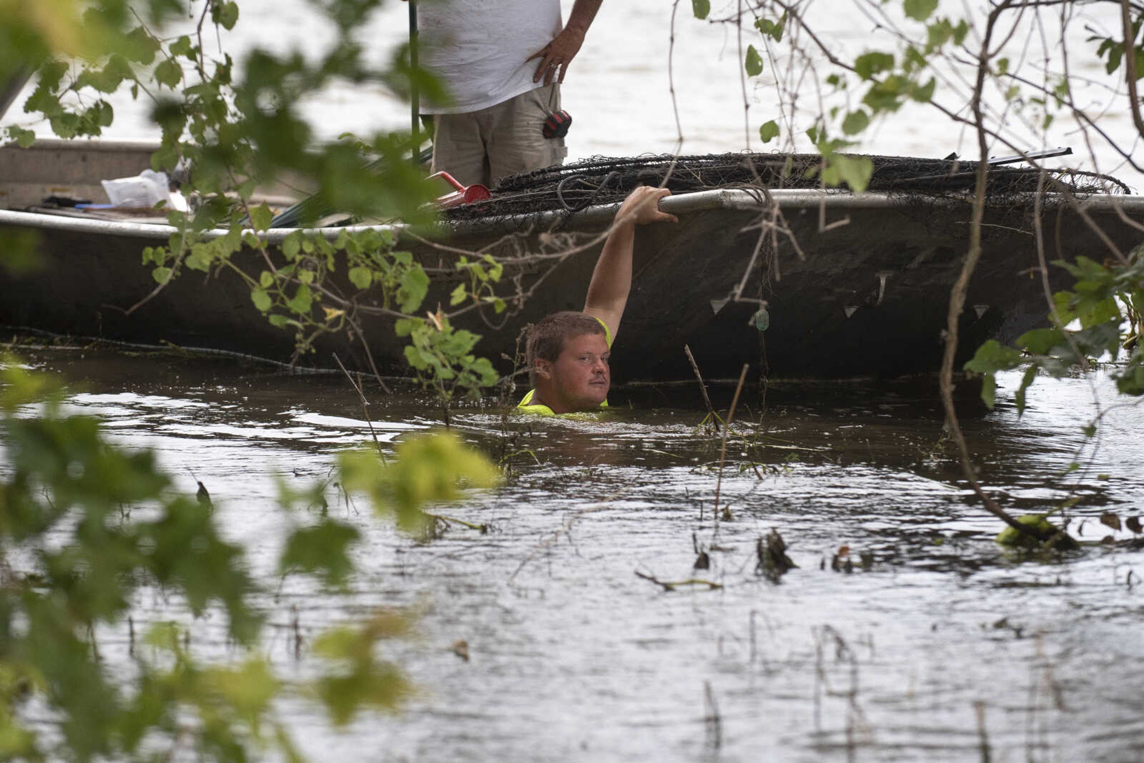 Toby Warner of East Cape Girardeau, Illinois, guides a boat containing Rick Smith of East Cape Girardeau while installing barriers to help slow waves on the floodwaters before the waves hit sandbag walls Sunday, July 14, 2019, in East Cape Girardeau, Illinois.