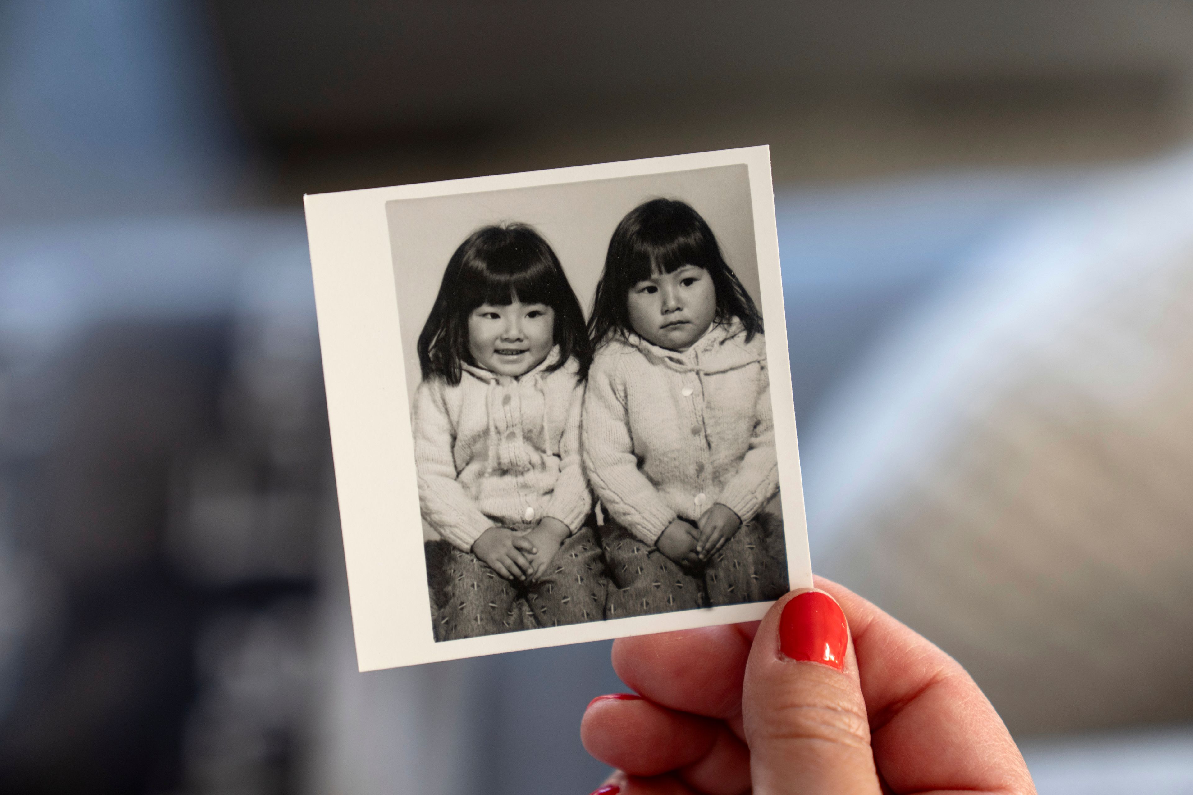 Becca Webster, holds a photo of herself at right, and her twin sister Dee Iraca, who were adopted out of South Korea to a family in the United States, Saturday, April 6, 2024, at Iraca's home in Davidson, N.C. Adopted by the same American family, their files described them as abandoned in front of a hospital. Anytime they thought about searching for their birth parents, they felt overwhelmed. (AP Photo/David Goldman)