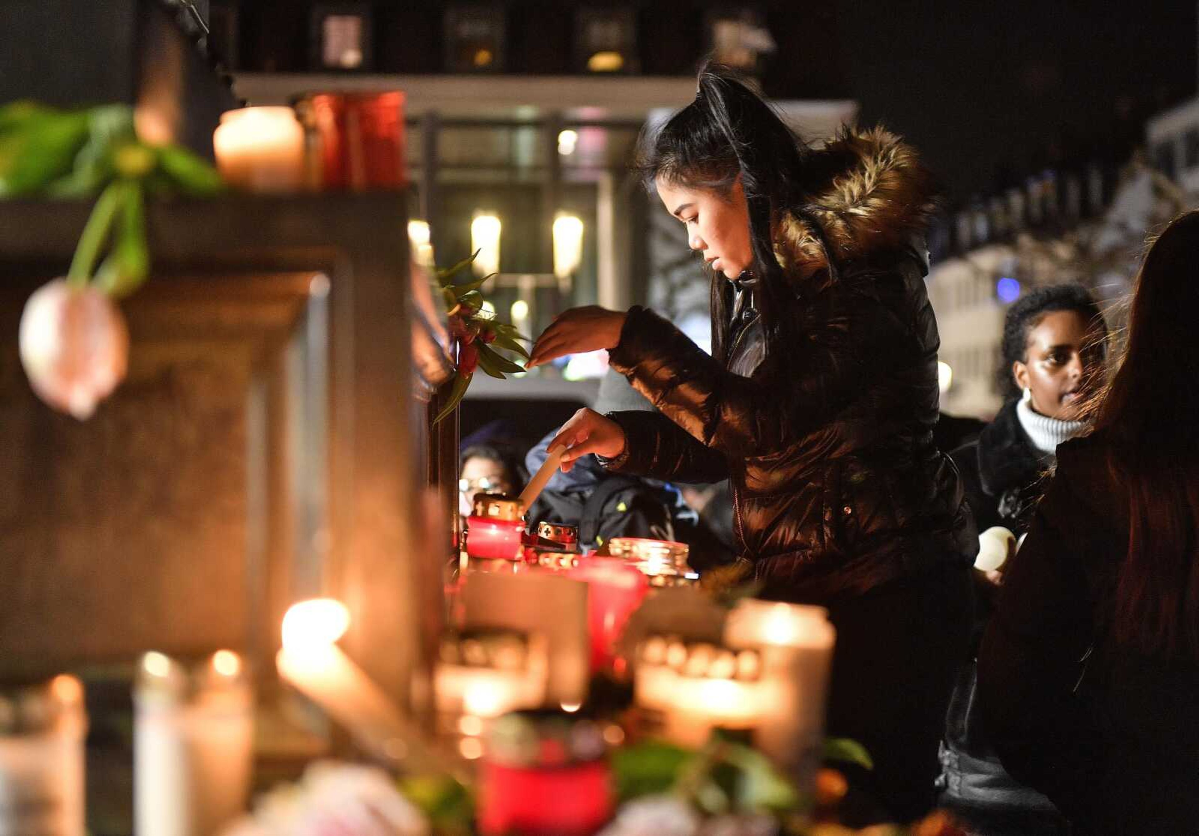 A woman lights a candle at a monument on the market place during a mourning for the victims of the shooting Thursday in Hanau, Germany.