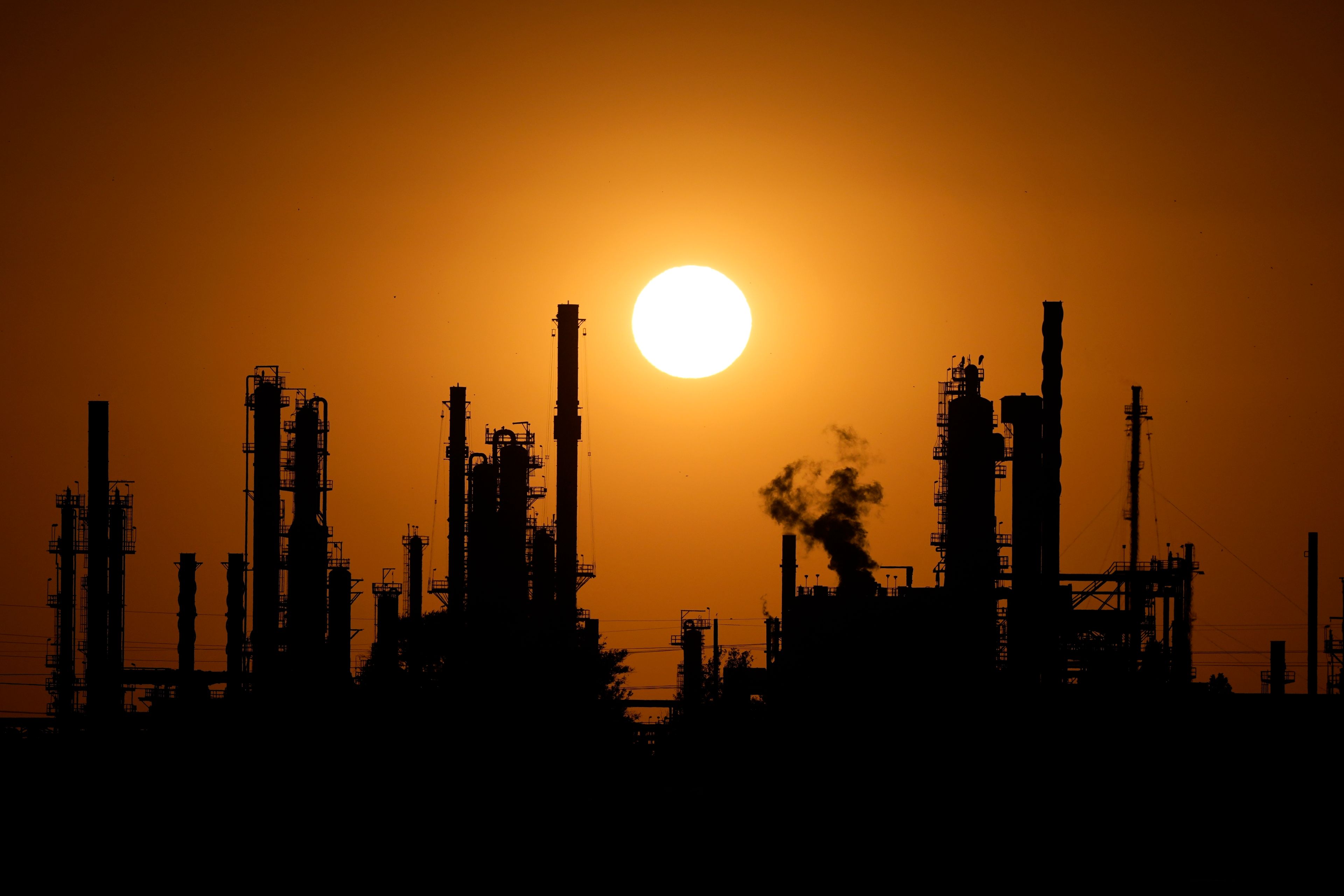 The CHS oil refinery is silhouetted against the setting sun Saturday, Sept. 28, 2024, in McPherson, Kan. (AP Photo/Charlie Riedel)