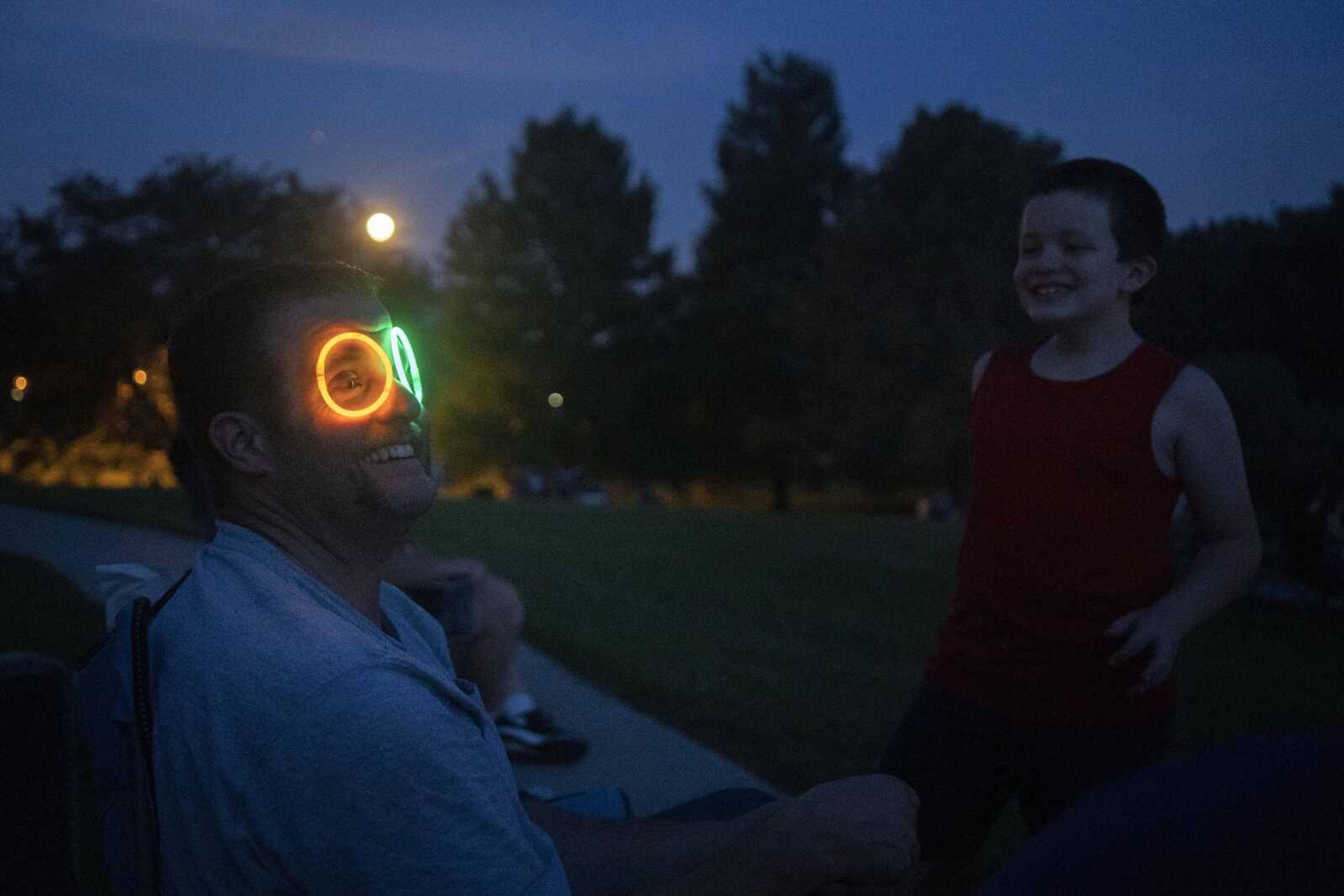 Daniel Puckett, left, makes a silly face after his son, Wesley, 7, right, put a pair of glow bracelets on his eyes while waiting for a fireworks show at the Jackson Municipal Band Shell.