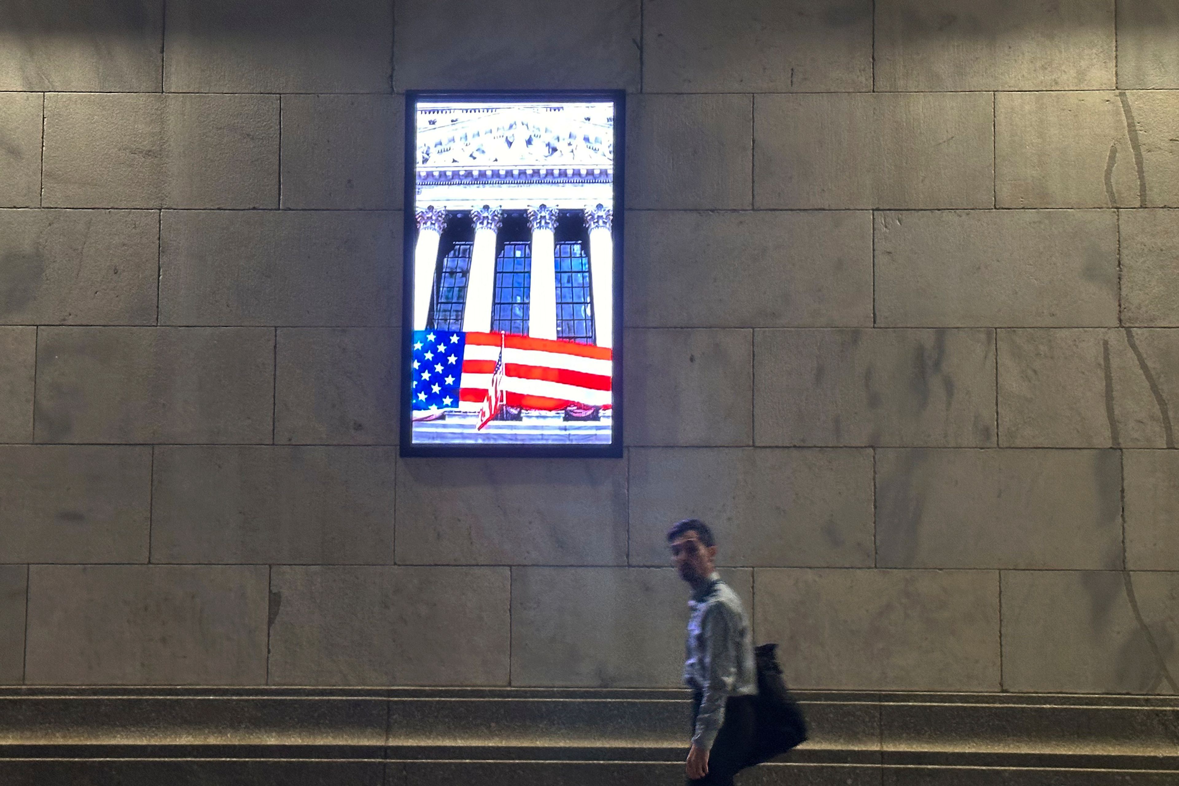 A man passes a video monitor on the side of the New York Stock Exchange in New York's Financial District on Tuesday, Nov. 5, 2024. (AP Photo/Peter Morgan)