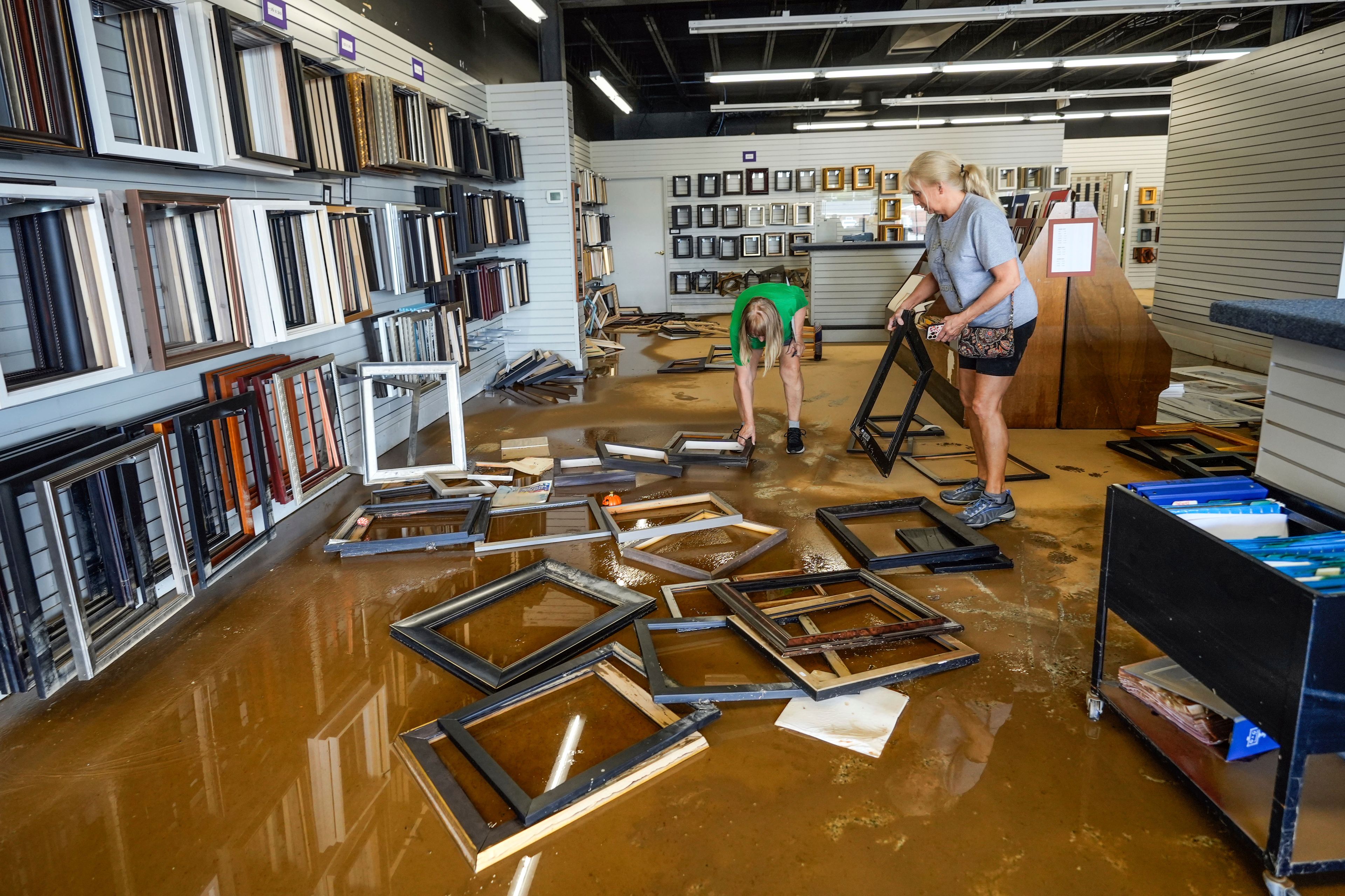 Employees Linda Bandy, left, and Carissa Sheehan clean up International Moulding frame shop damaged by flood water from Hurricane Helene on North Green Street, Monday, Sept. 30, 2024, in Morganton, N.C. (AP Photo/Kathy Kmonicek)